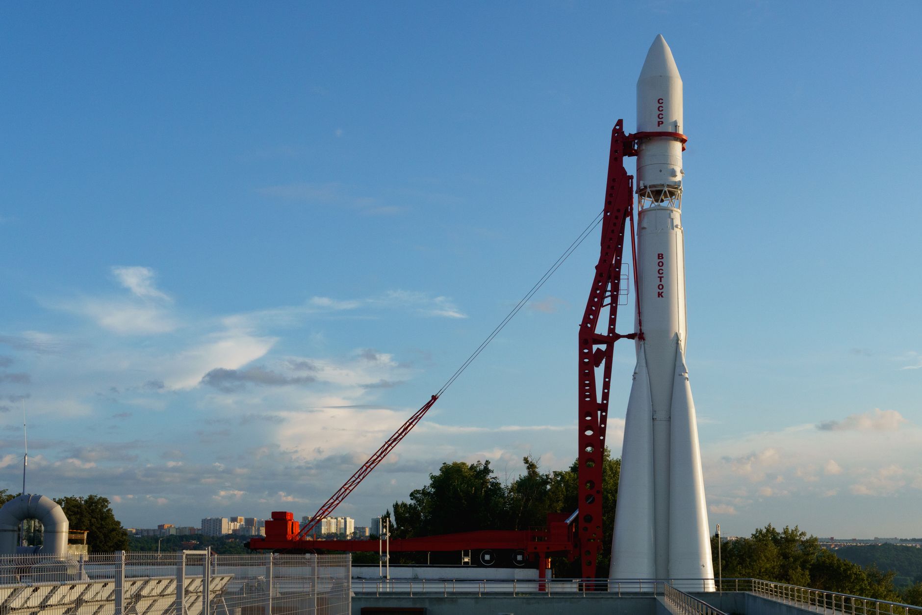 a private aerospace launch facility at dusk, a large orbital rocket standing vertical on the pad under floodlights, surrounded by industrial scaffolding and flat scrubland