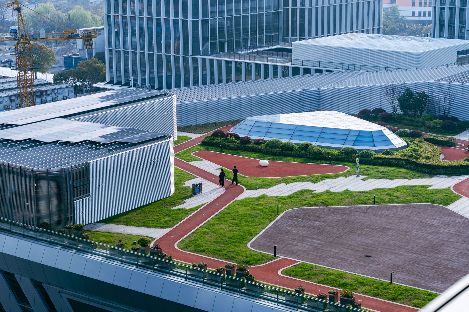 aerial view of a modern Tel Aviv tech campus with glass office buildings and rooftop solar panels under afternoon light