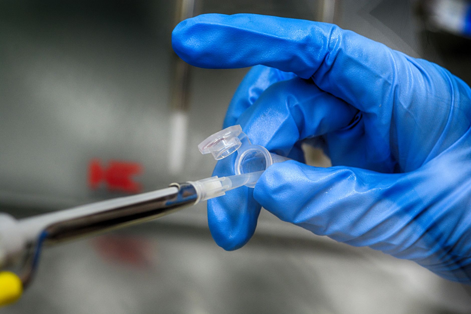 rows of biological sample vials in a temperature-controlled laboratory storage unit, with soft blue ambient lighting and automated retrieval arms in the background