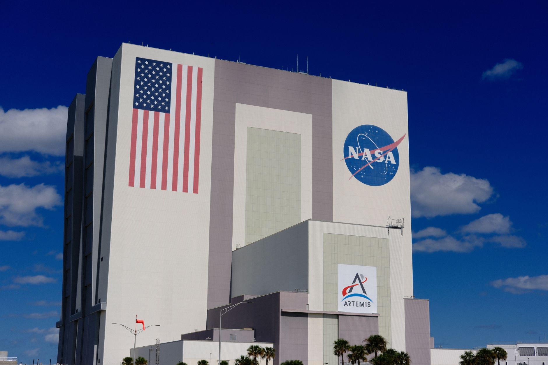 a wide-angle view of a rocket engine test stand at a remote desert launch facility, with exhaust flame trenches and support scaffolding visible under a clear afternoon sky