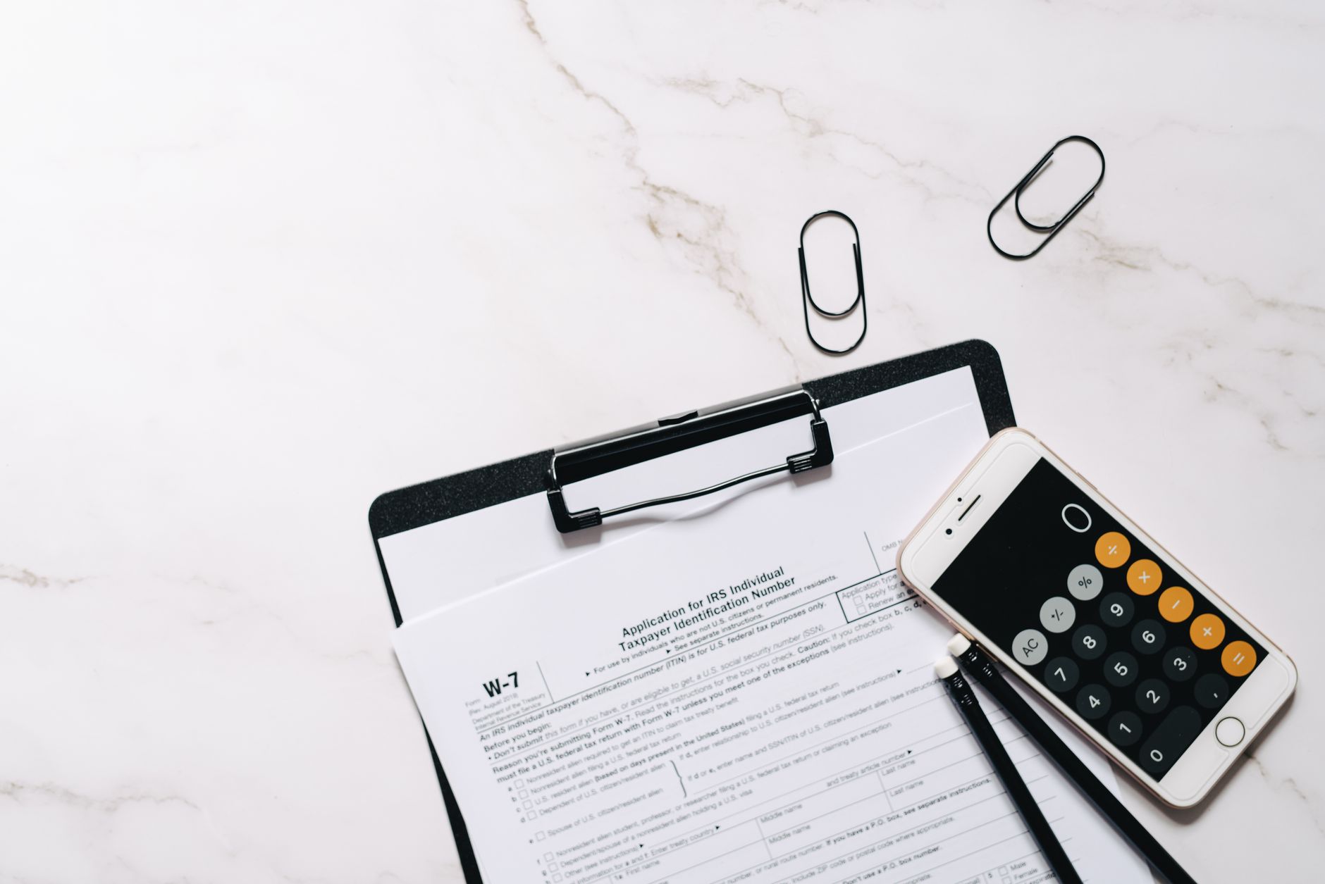 close-up of a stack of tax documents and a W-2 form on a wooden desktop, softly lit from a nearby window