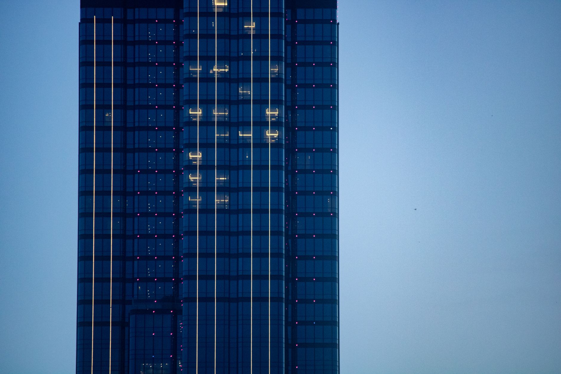exterior of a modern financial district tower at dusk, glass facade reflecting city lights, signage removed