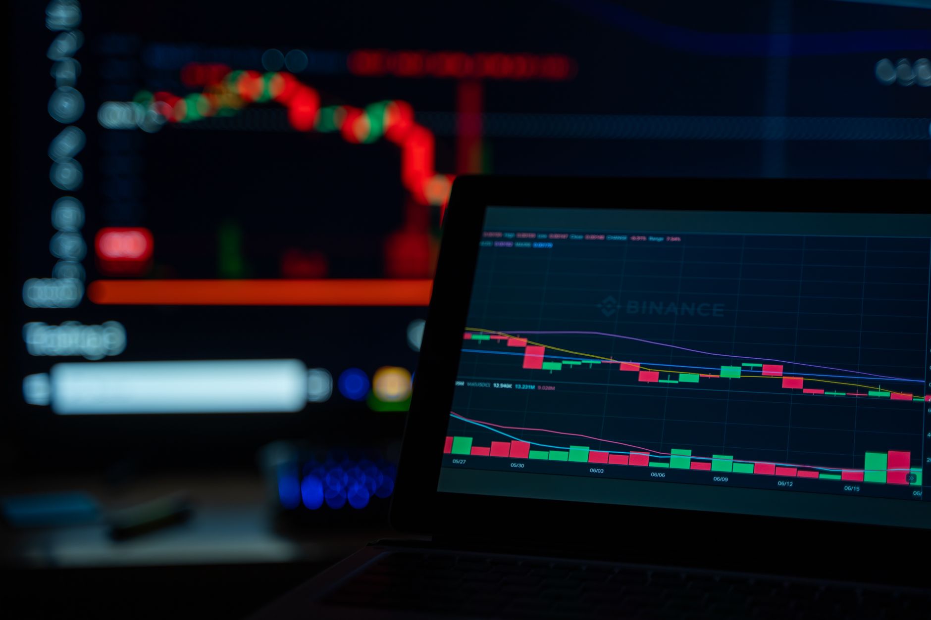 rows of computer terminals displaying cryptocurrency trading data on dark-mode dashboards in an open-plan office