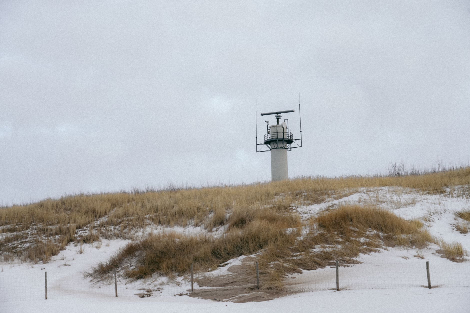 an aerial surveillance radar array mounted on a rotating platform atop a coastal watchtower overlooking open ocean