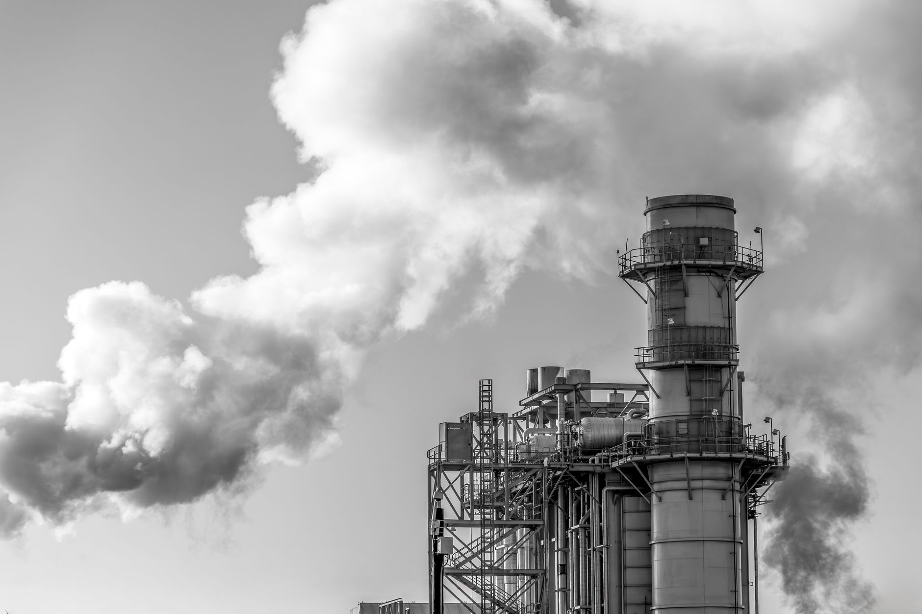 exterior view of a large Soviet-era industrial manufacturing complex, partially obscured by heavy smoke rising from one wing of the structure