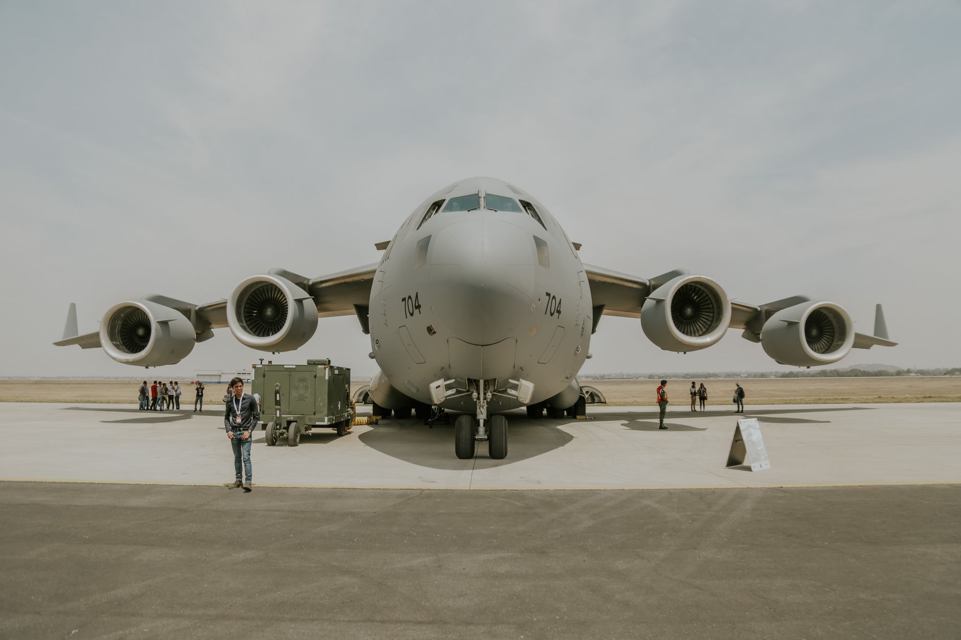a long-range cruise missile mounted on a ground-launch vehicle on a concrete military airfield, surrounded by support equipment under an overcast sky