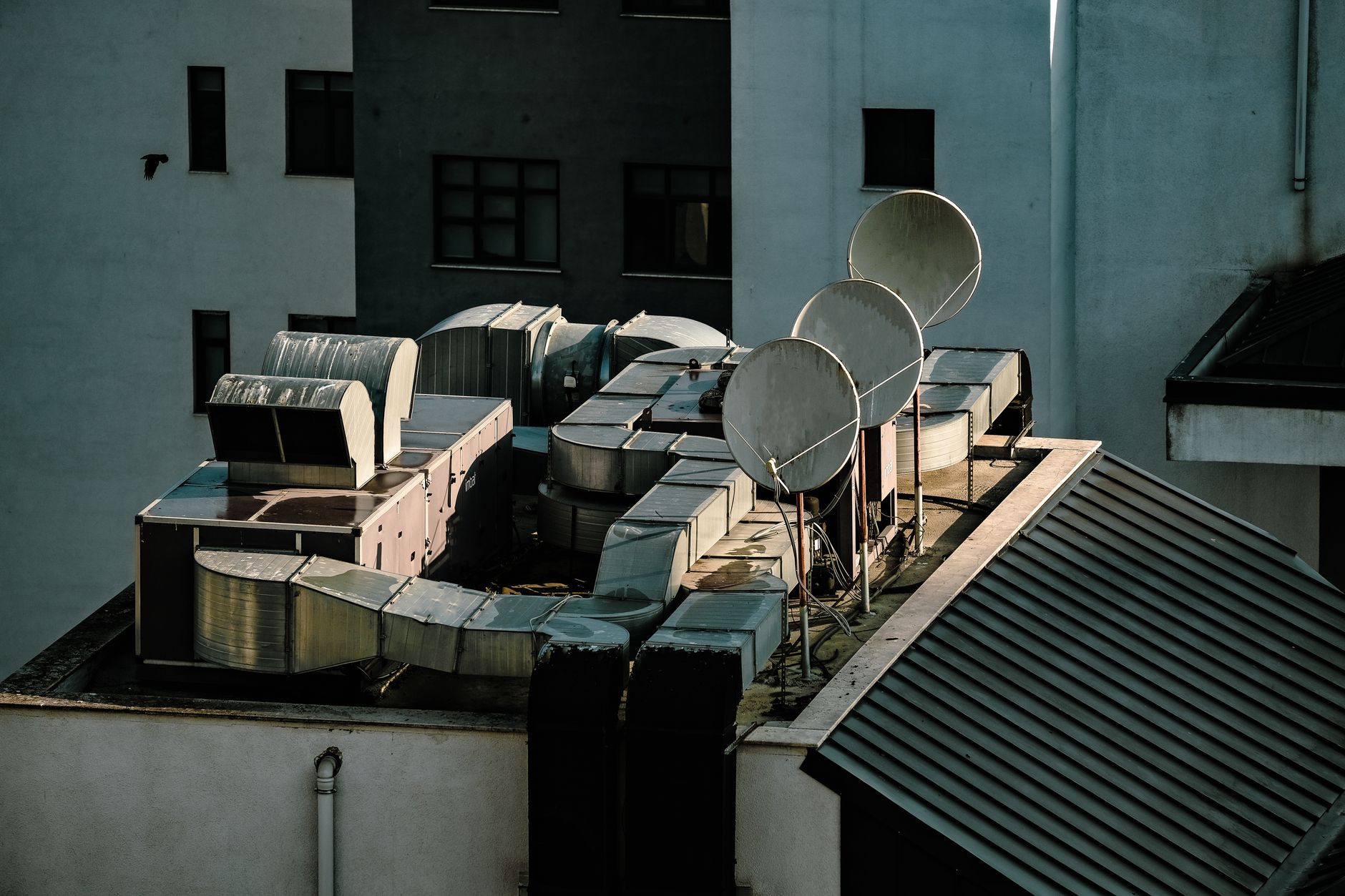 a wide aerial shot of a modern government diplomatic complex with satellite dishes and communications towers visible on the rooftop, set against an overcast sky