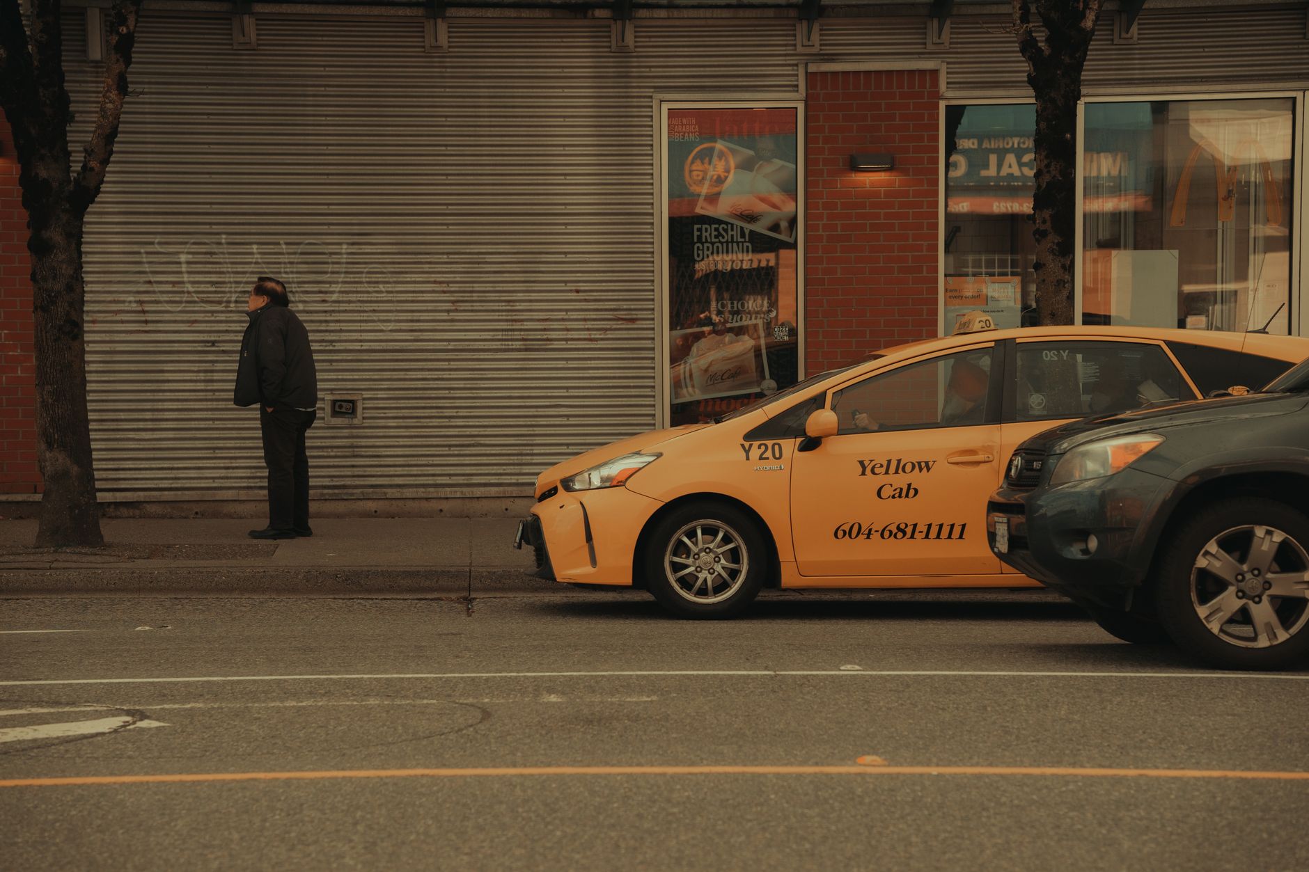 wide-angle view of an empty downtown commercial street with closed storefronts and a few parked delivery vehicles in the foreground