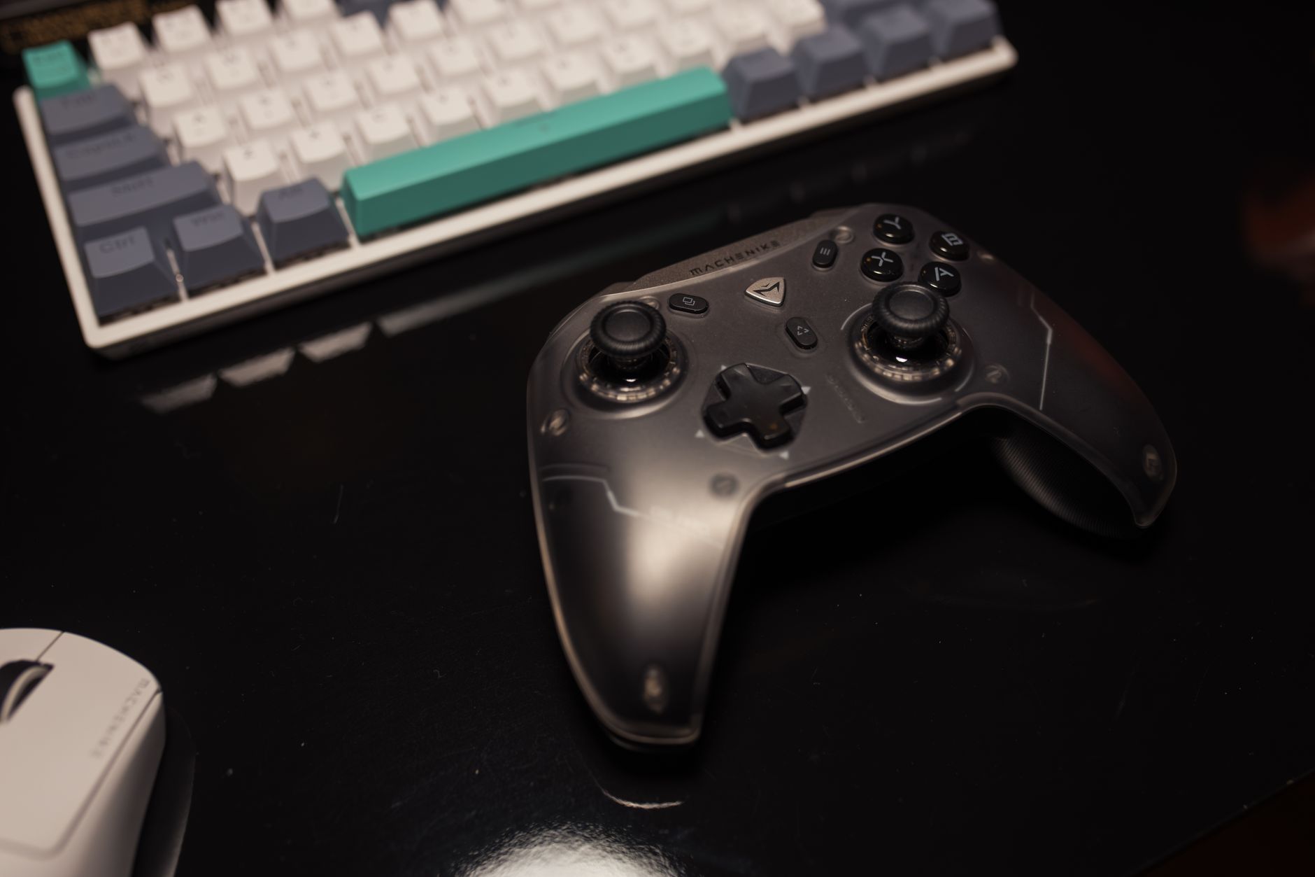 A gaming controller resting beside a monitor displaying a game settings menu, with thumbstick accessories and replacement paddles arranged on the desk surface nearby, suggesting a high-end peripheral setup