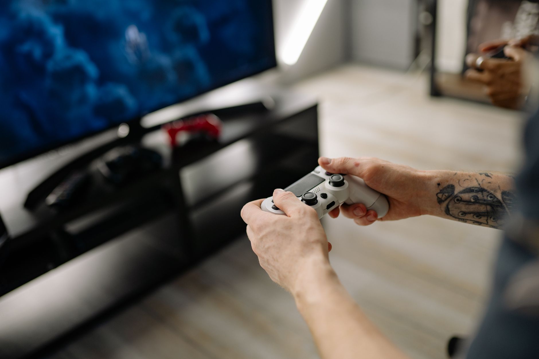 a modern gaming setup with a large 4K display showing a game menu, a sleek console unit positioned beneath it, and a wireless controller resting on a desk