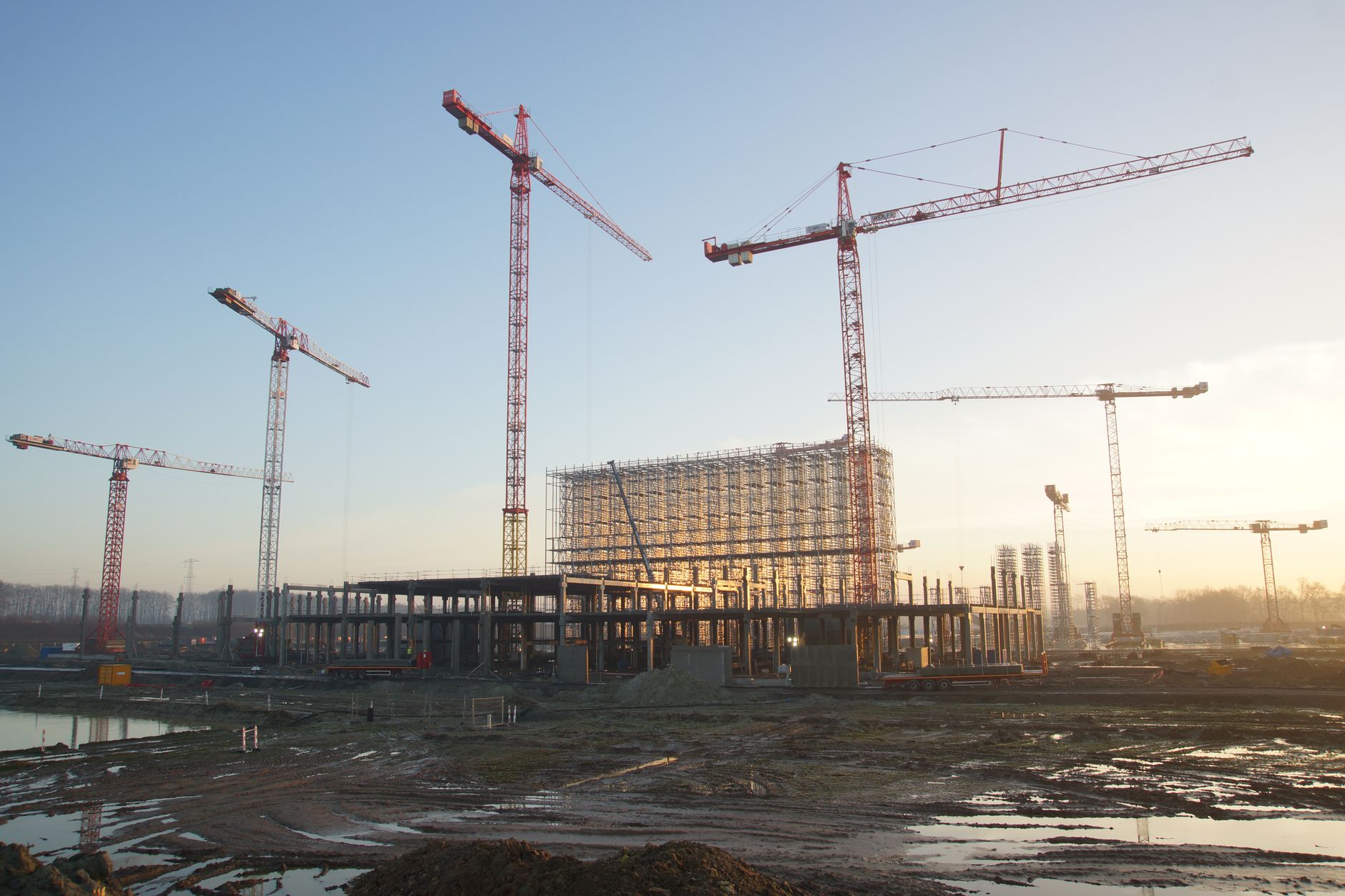 aerial view of a large-scale data center campus under construction in a flat rural landscape, with heavy equipment and partially completed steel-frame buildings visible