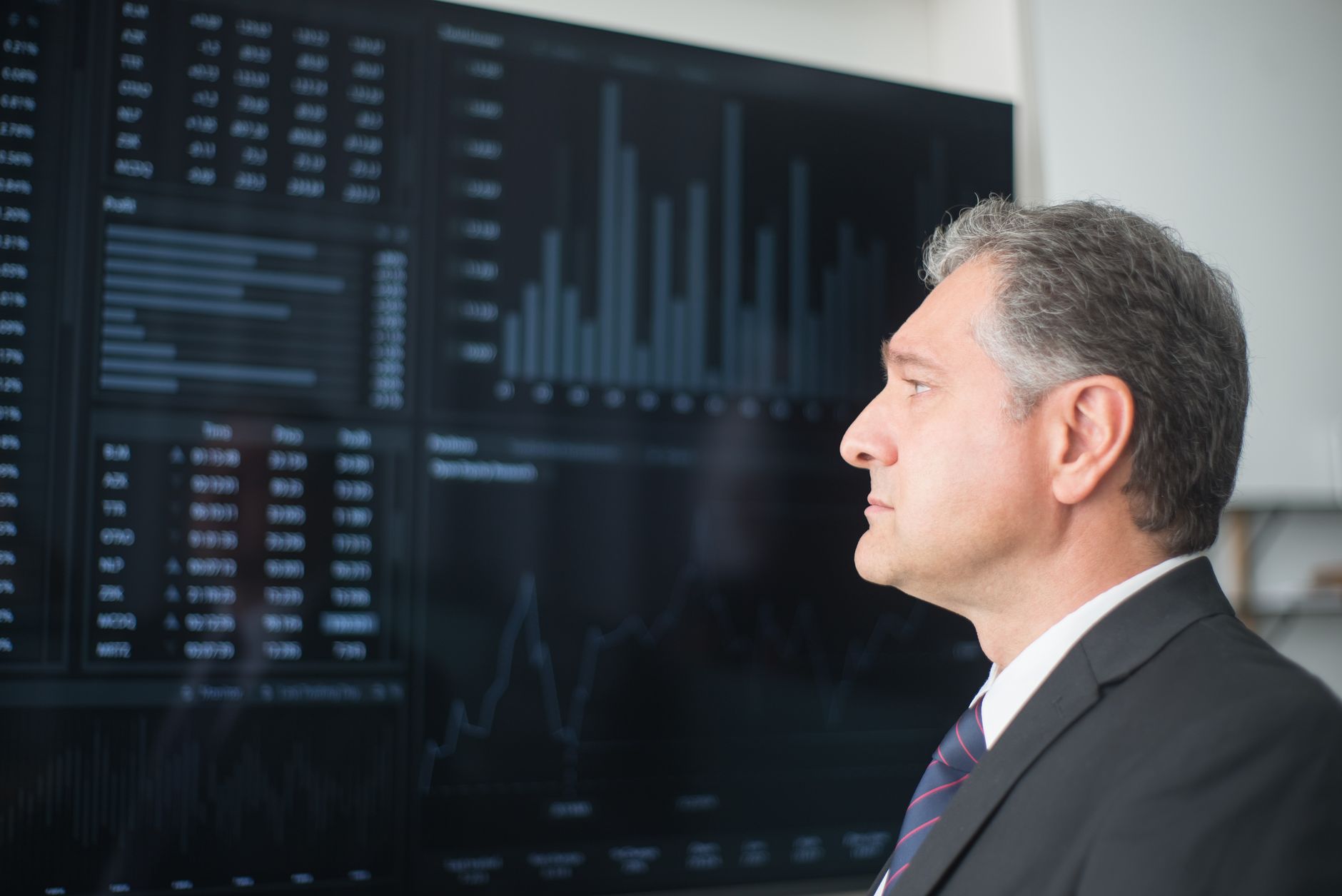 a close-up of a large touchscreen display in a conference room showing a graph of AI model capability benchmarks climbing steeply over time, with threshold lines marked across the chart