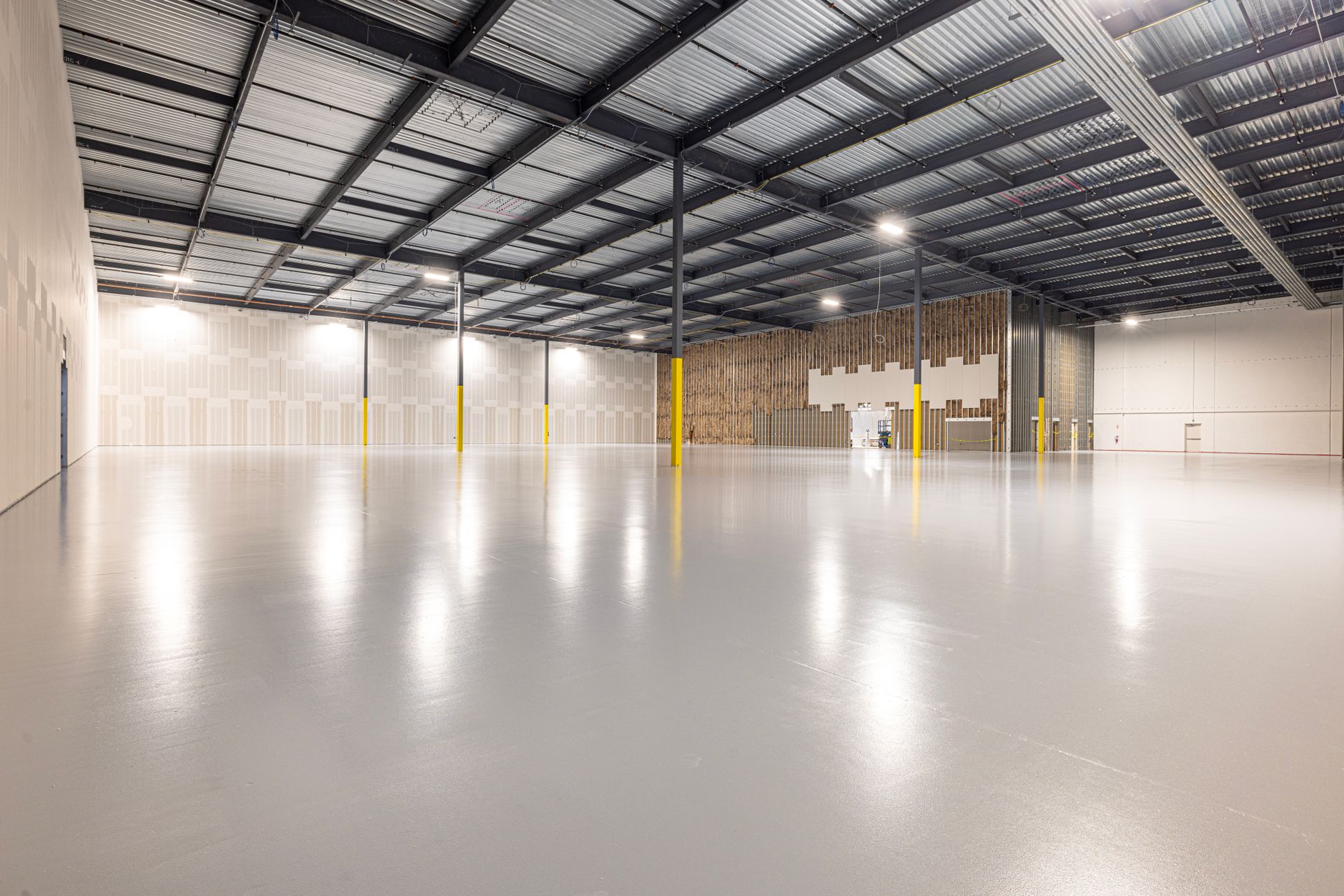 a wide-angle view of warehouse-scale server infrastructure inside a large distribution facility, with conveyor systems visible in the background