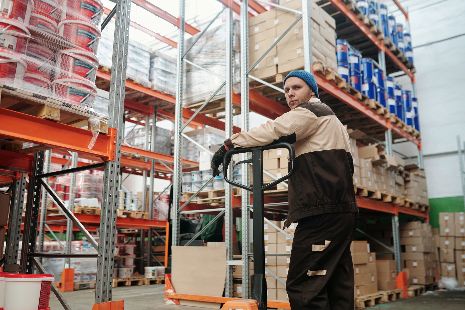 rows of cargo containers and freight pallets staged inside a large airport logistics terminal, with conveyor equipment visible along the walls