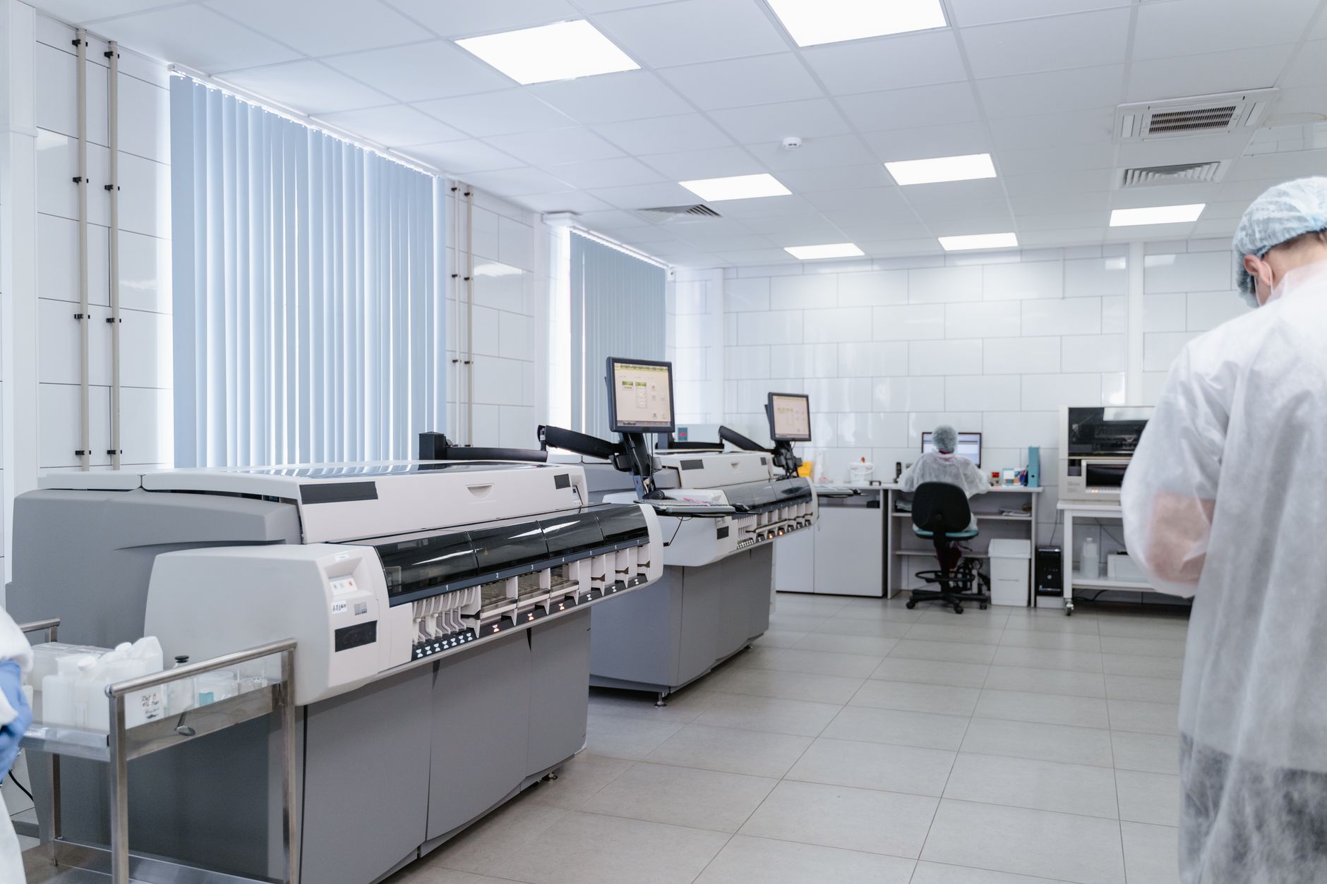 a modern biotech research laboratory interior with centrifuge machines and illuminated cell culture incubators visible along a stainless steel workbench