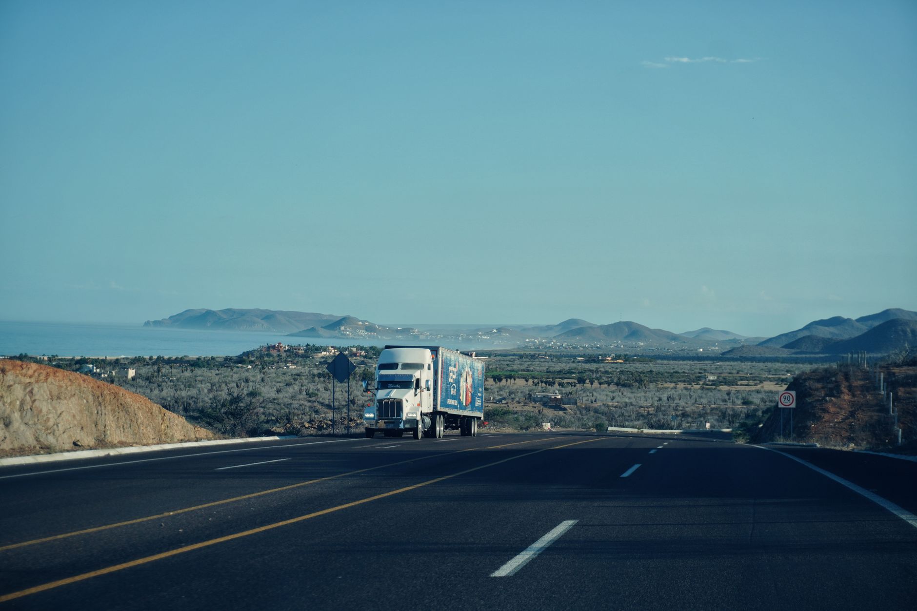 a long-haul semi-truck cab viewed from low angle on an open Texas highway at early morning, no driver visible through the windshield, vast flat landscape stretching to the horizon