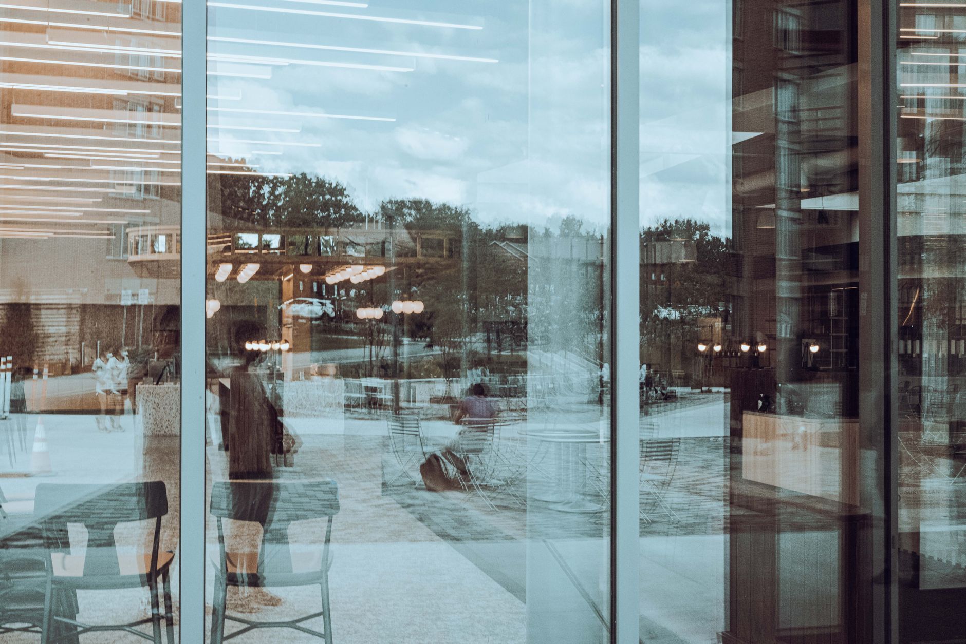 a glass-walled modern office building exterior at dusk with ambient interior lighting visible through the windows, set in an urban tech campus