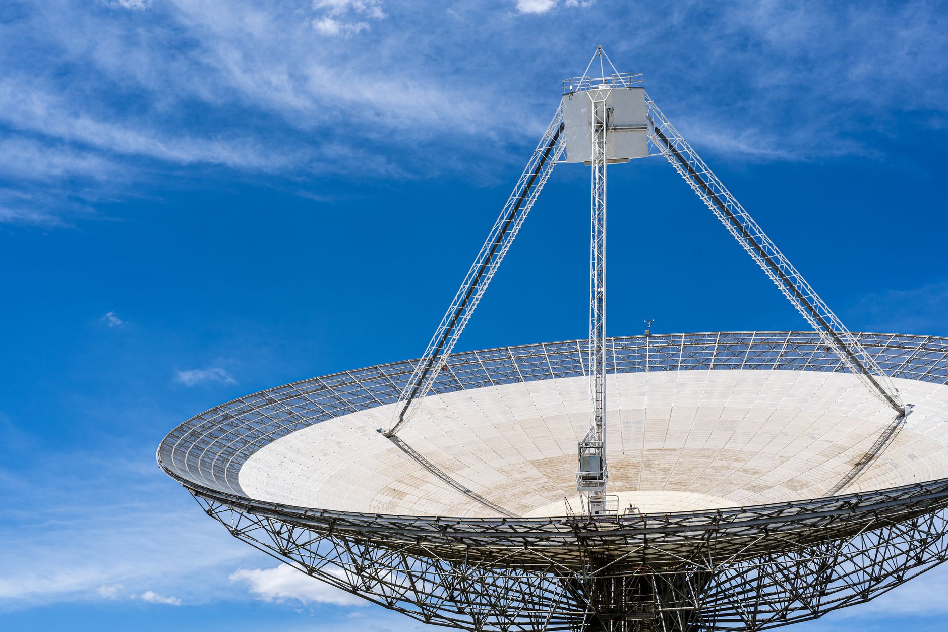 a false-color radio telescope dish array angled toward the outer solar system at dawn, with instrument cables and equipment visible in the foreground