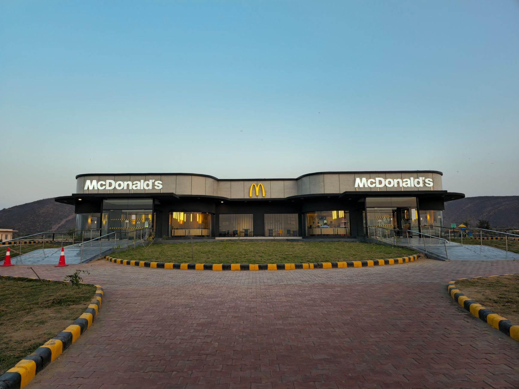 exterior of a modern fast-casual restaurant building with drive-through lane and clean architectural signage, shot at golden hour