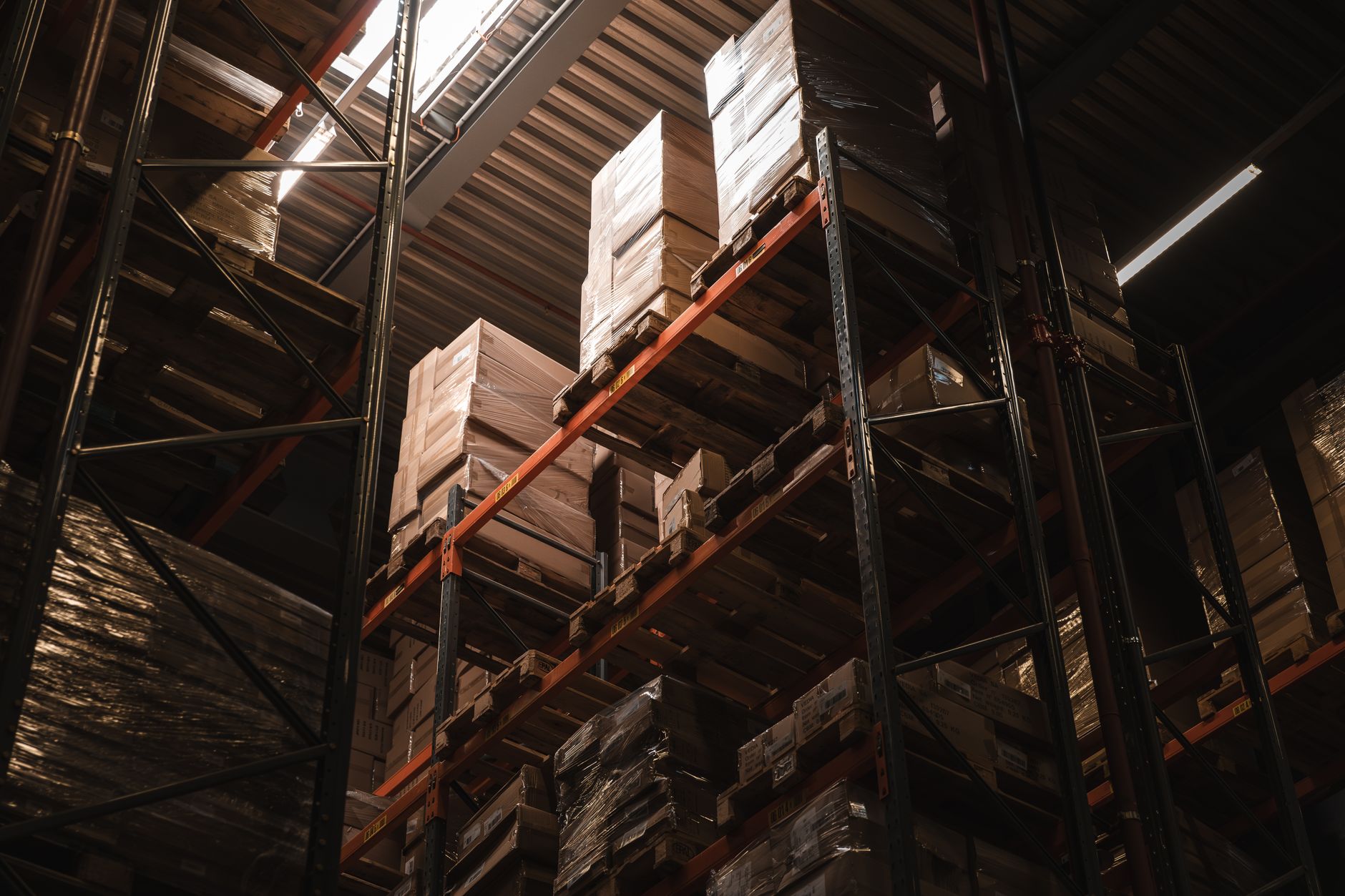 rows of supply chain logistics containers at a large food distribution warehouse, shot from an elevated angle showing organized pallet rows and overhead lighting