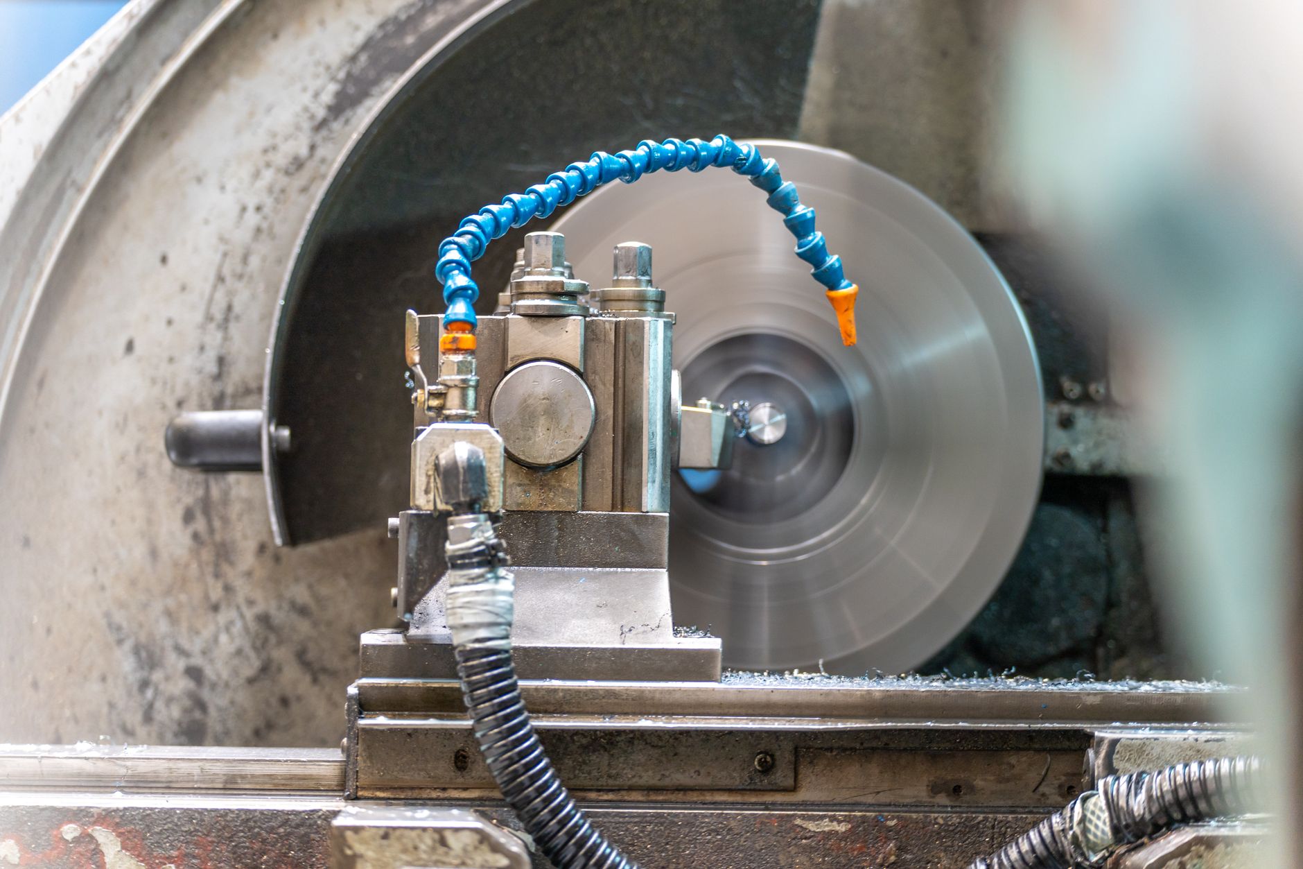 rows of CNC milling machines on a factory floor with metal shavings collected beneath the cutting heads, shot from a low wide angle