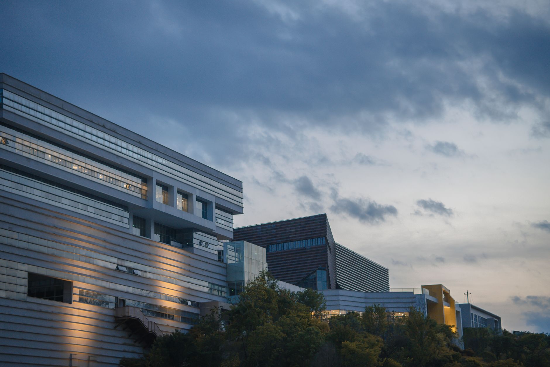 wide-angle view of a sprawling corporate data center campus exterior at dusk, rows of ventilation units visible along the building facade