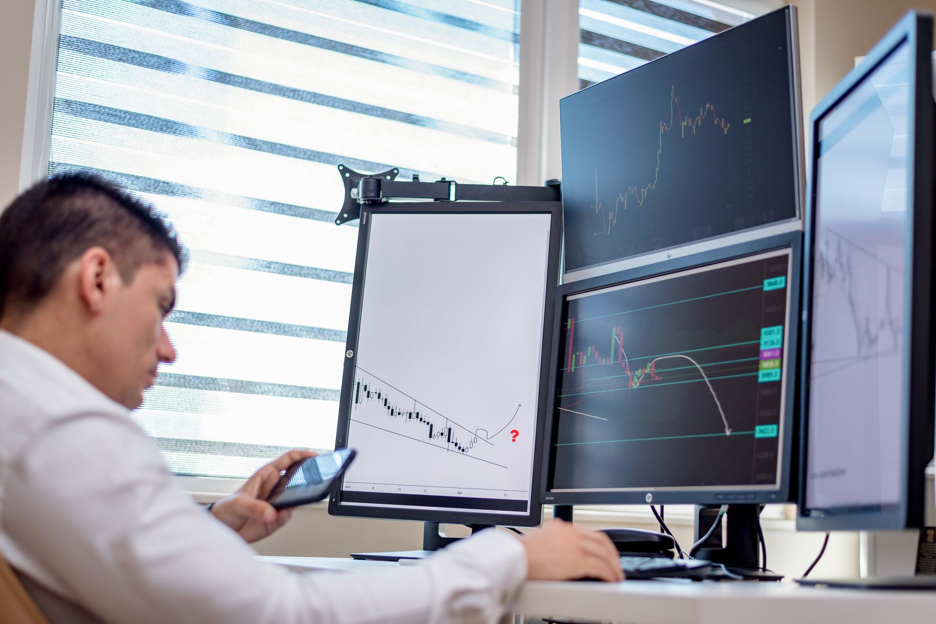 close-up of stock trading terminal screens displaying financial charts and transaction data in a dimly lit office environment