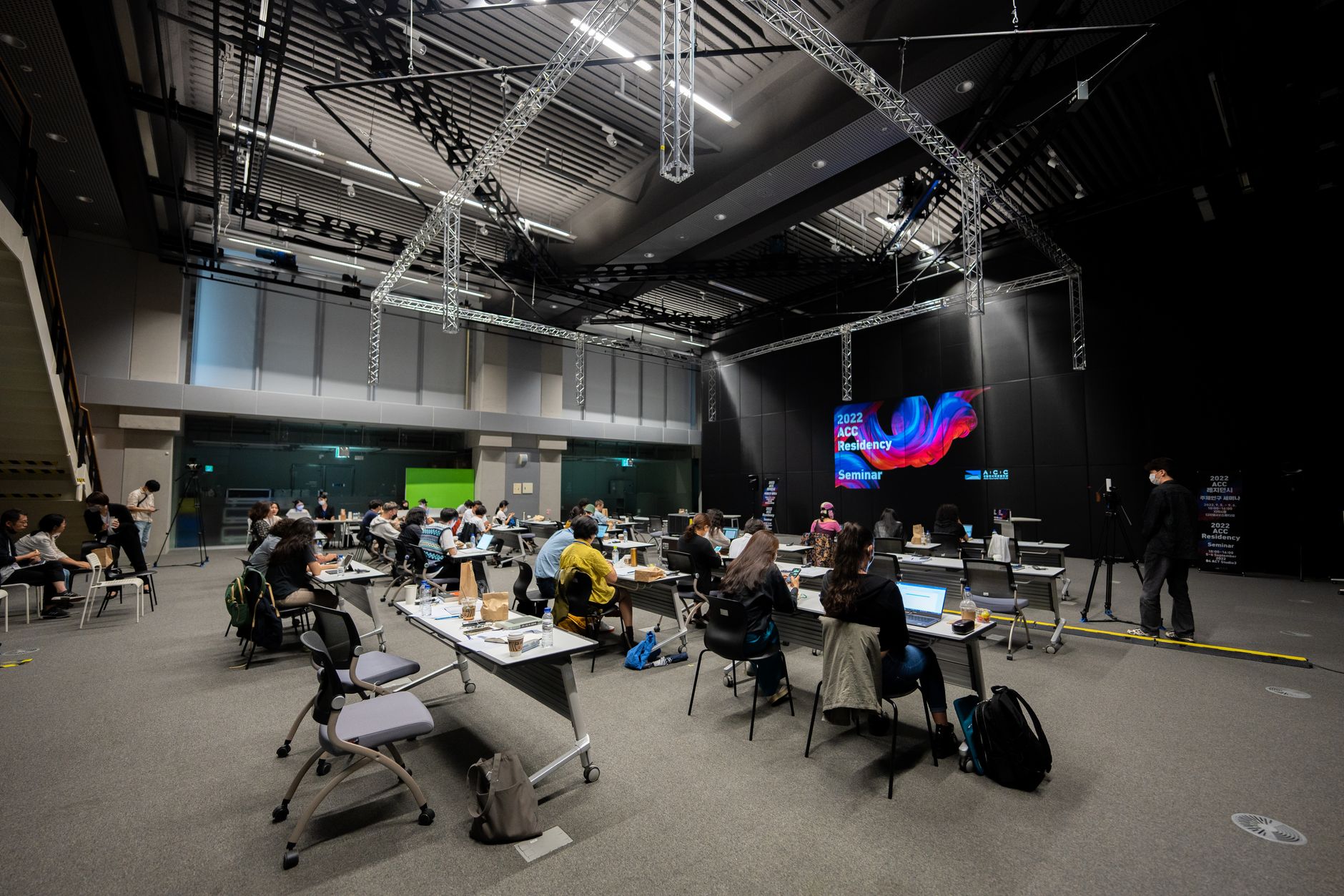 a wide-angle view of a large neuroscience conference hall with tiered seating and presentation screens displaying brain scan imagery