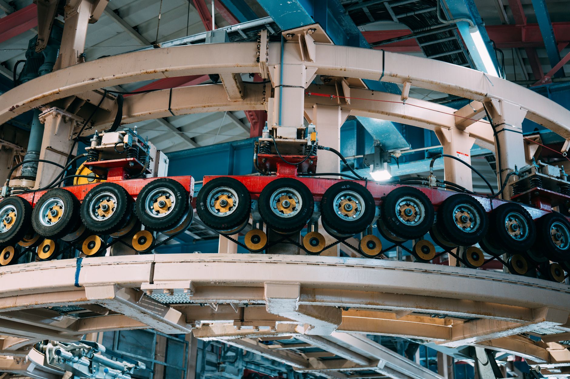 wide-angle view of a large aerospace manufacturing floor with cylindrical space module components positioned on assembly stands under bright overhead lighting