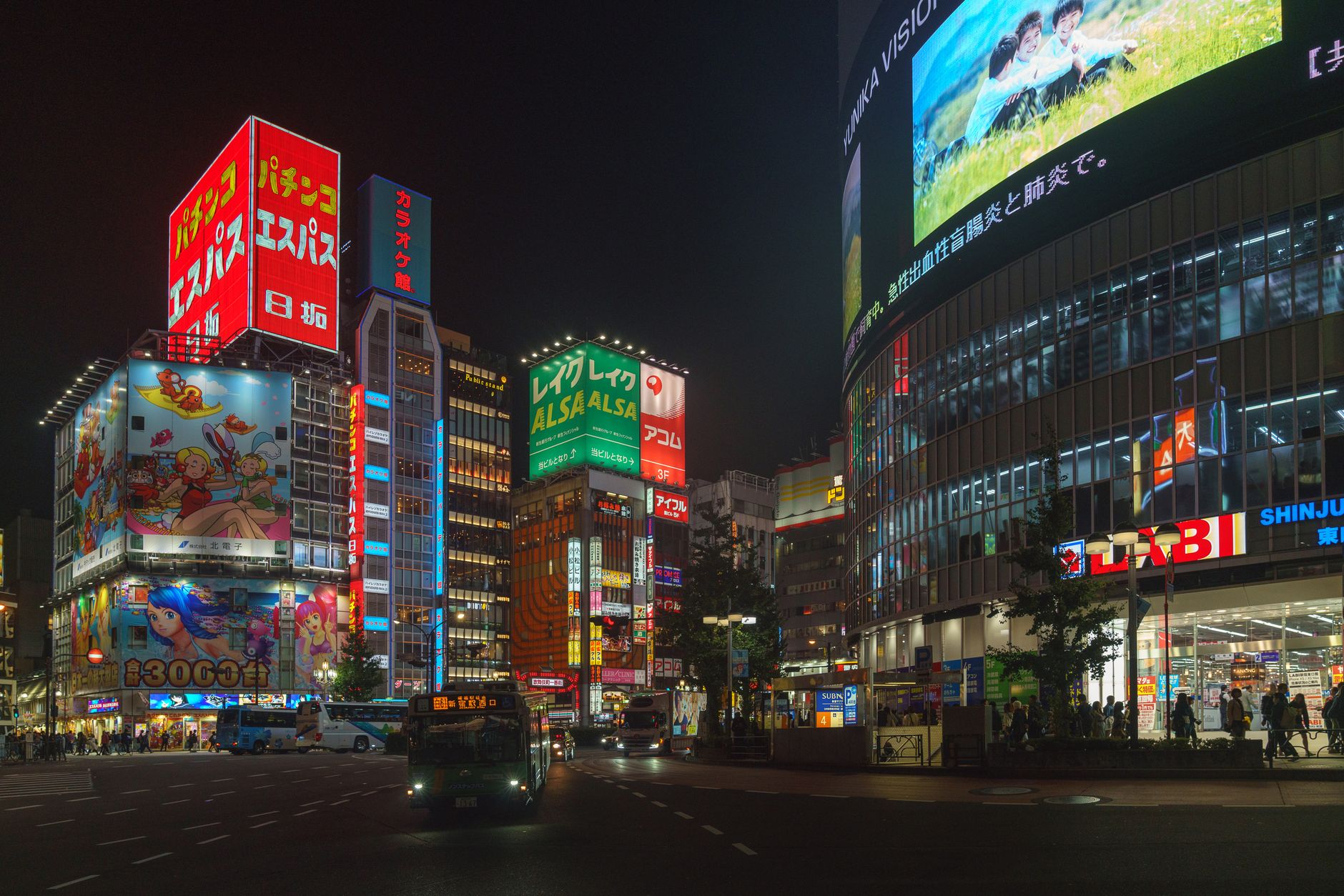 a large flat-screen TV mounted in a dimly lit living room displaying an open-world city game environment with neon-lit streets at night