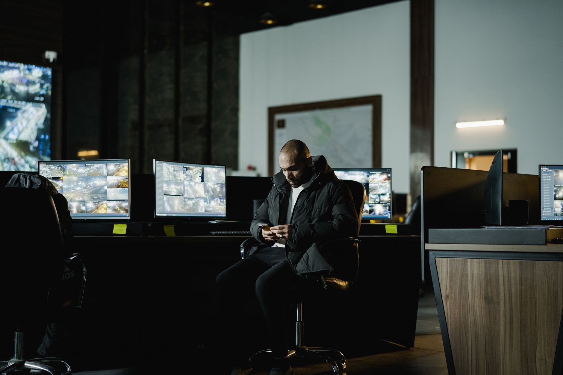 a wide-angle view of a modern enterprise security operations center with multiple monitor screens displaying live camera feeds, access logs, and alert dashboards