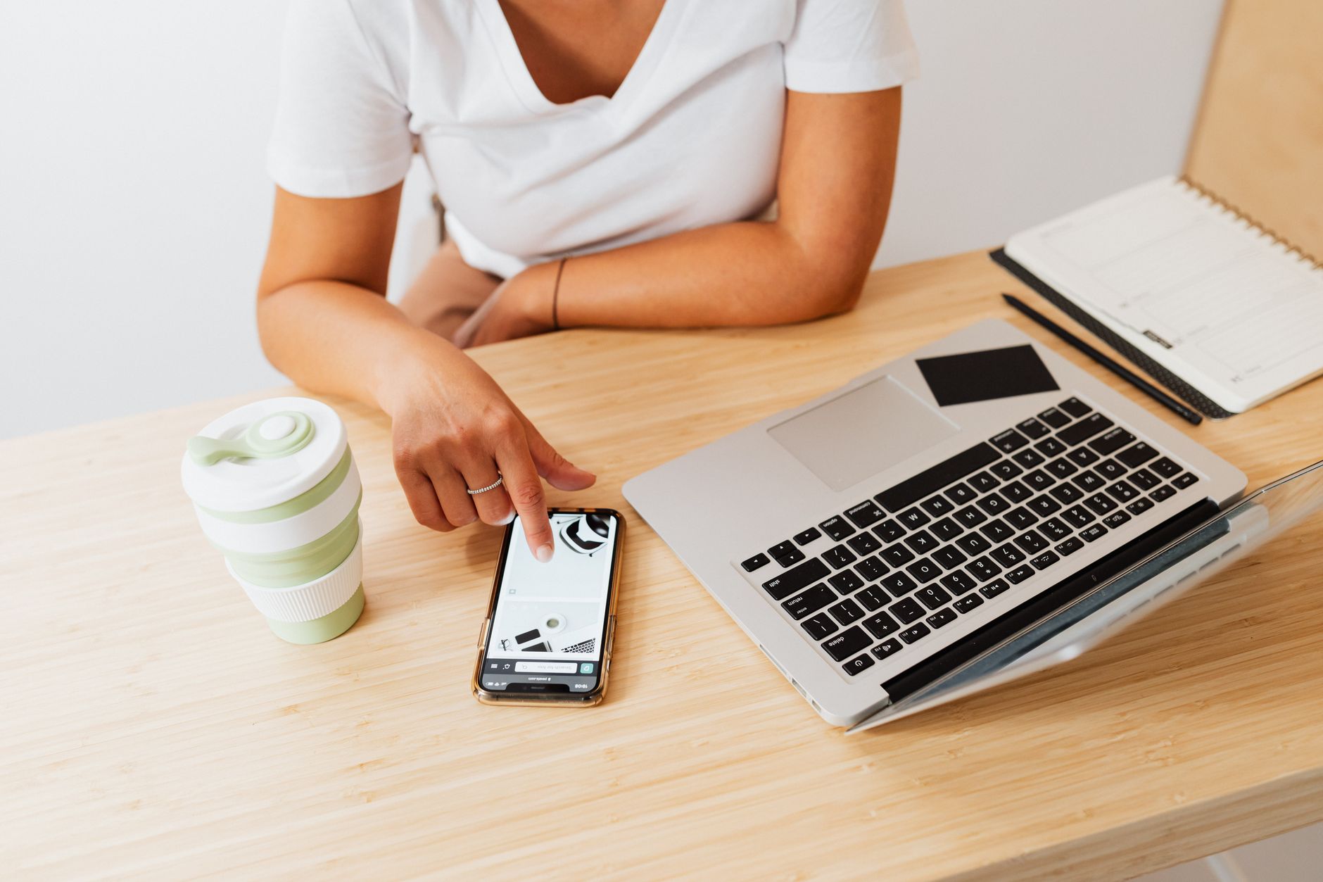 a close-up of an iPhone screen showing the Safari settings menu with toggle switches, resting on a wooden desk beside a coffee cup