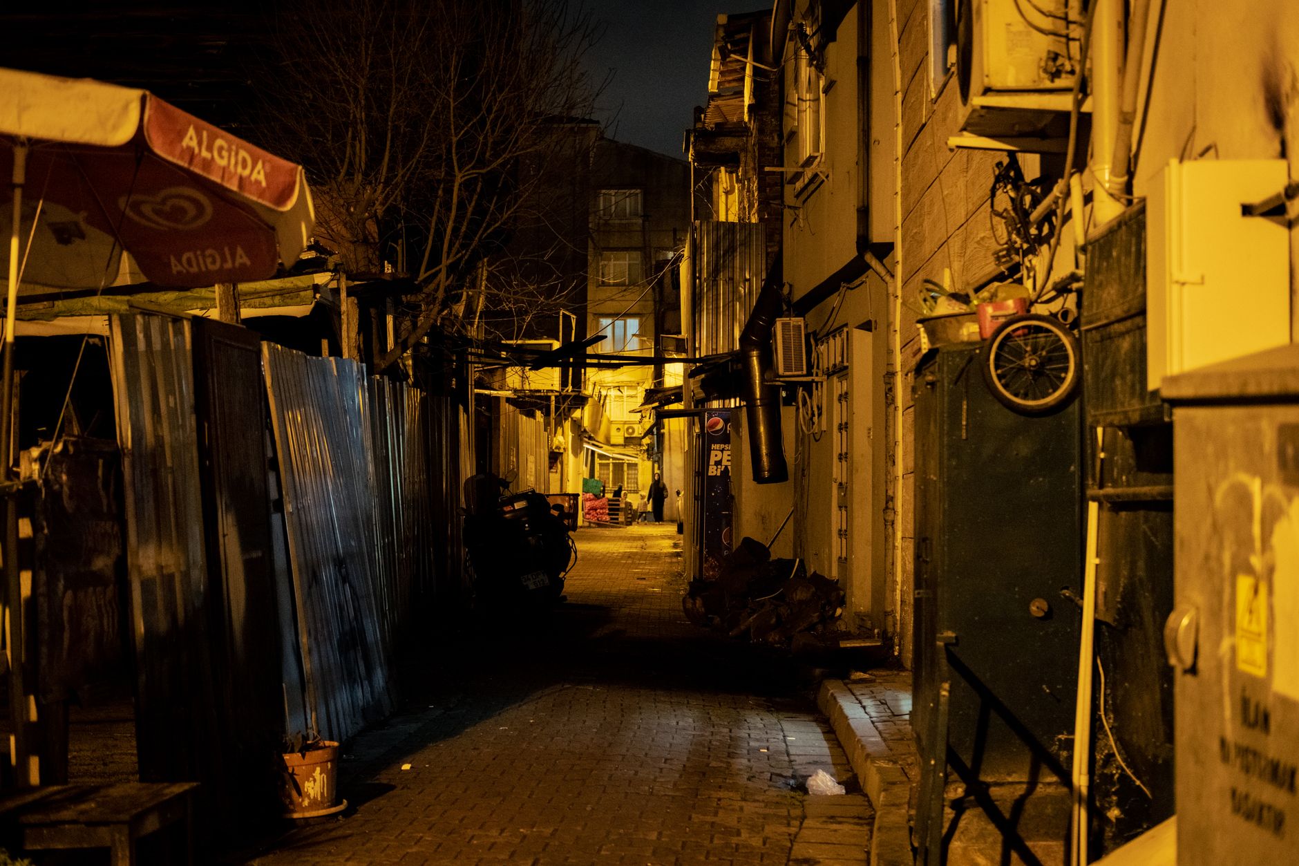 a smartphone displaying a high-detail low-light photograph of a dimly lit urban street, screen visible in a dark room