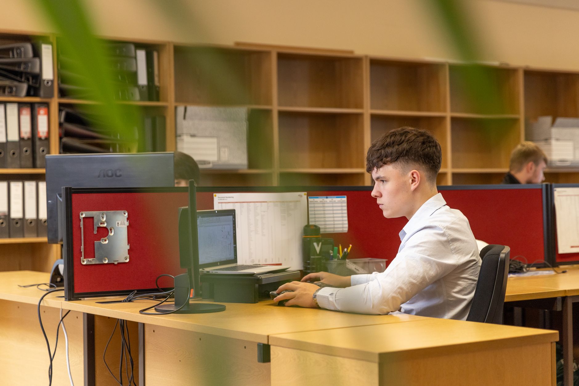 rows of generic desktop workstations in a dimly lit corporate investigation firm office, screens showing document analysis software, no people in frame