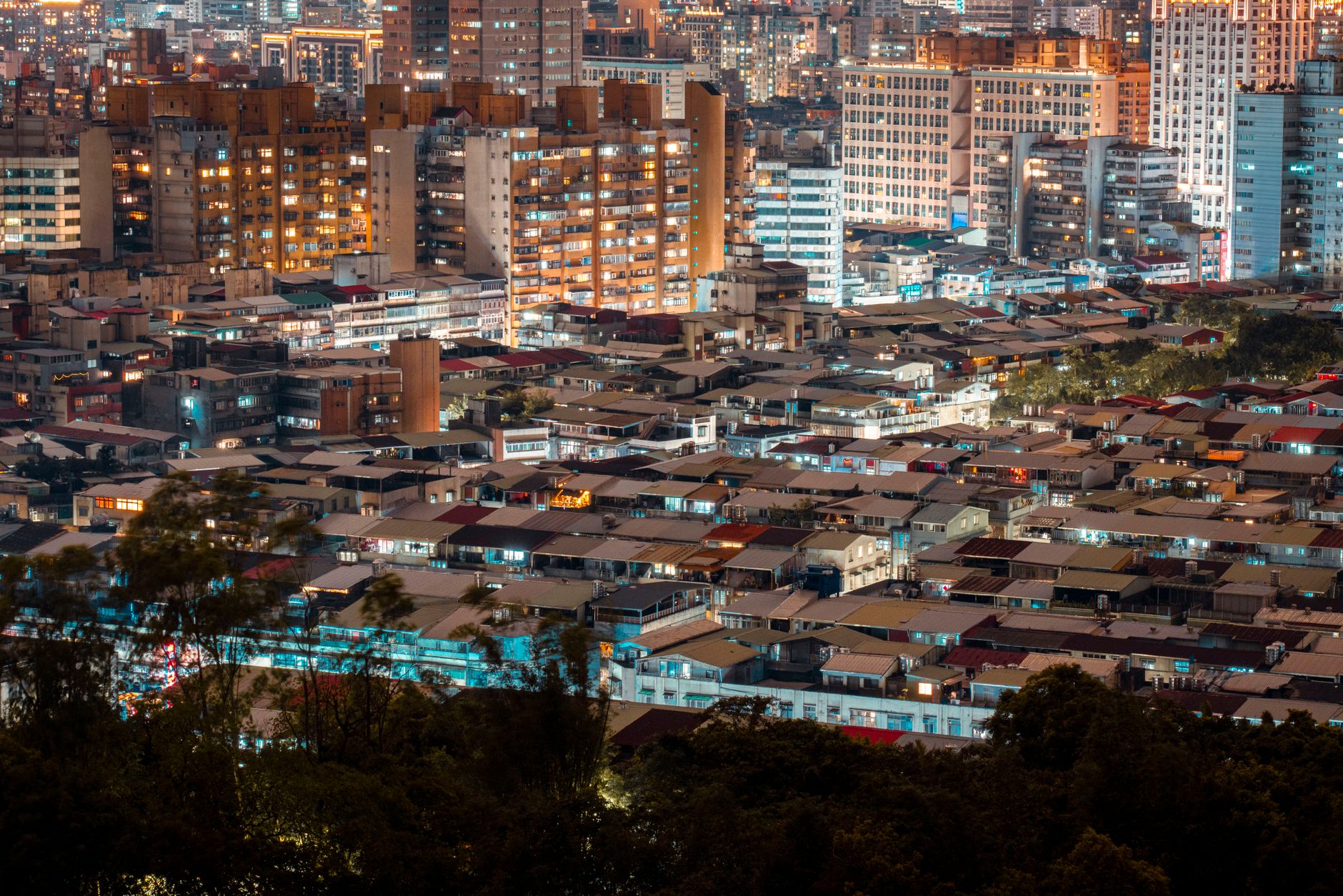 aerial view of a dense urban skyline at dusk with glowing office towers and rooftop antenna arrays, representing a concentrated technology hub