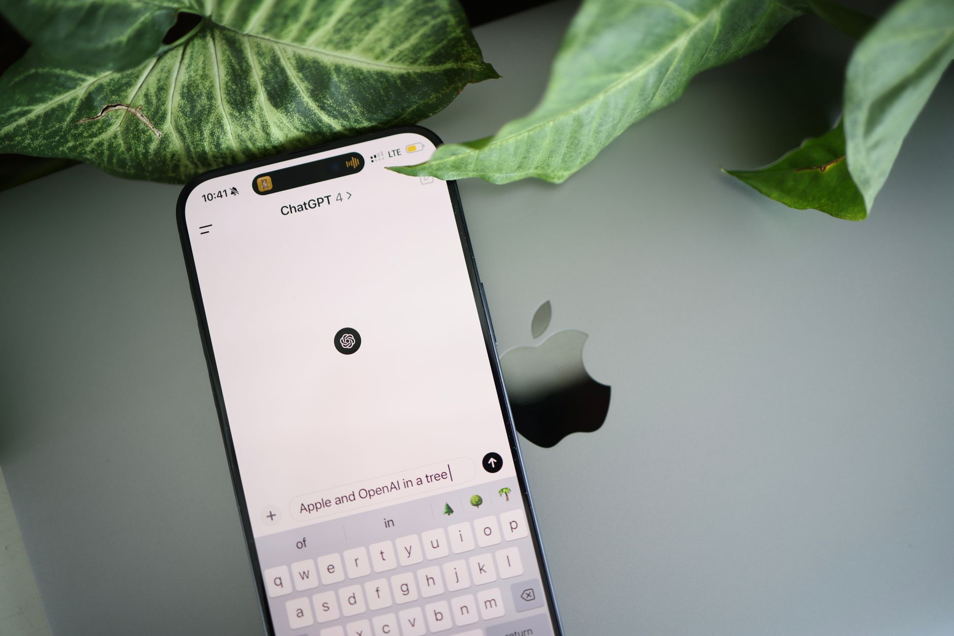 a smartphone screen showing a conversational AI chat interface with English dialogue bubbles, resting on a wooden desk beside a notebook