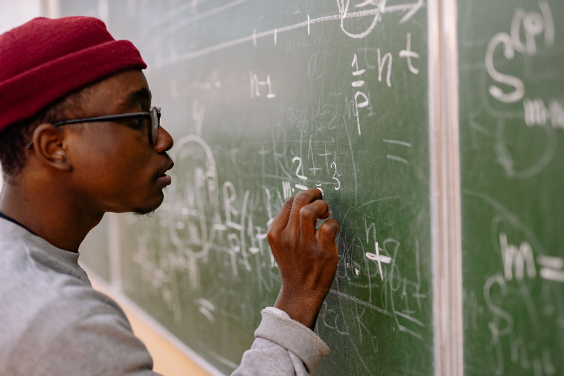 a large university lecture hall with a chalkboard covered in mathematical equations and proofs, empty seats facing the board