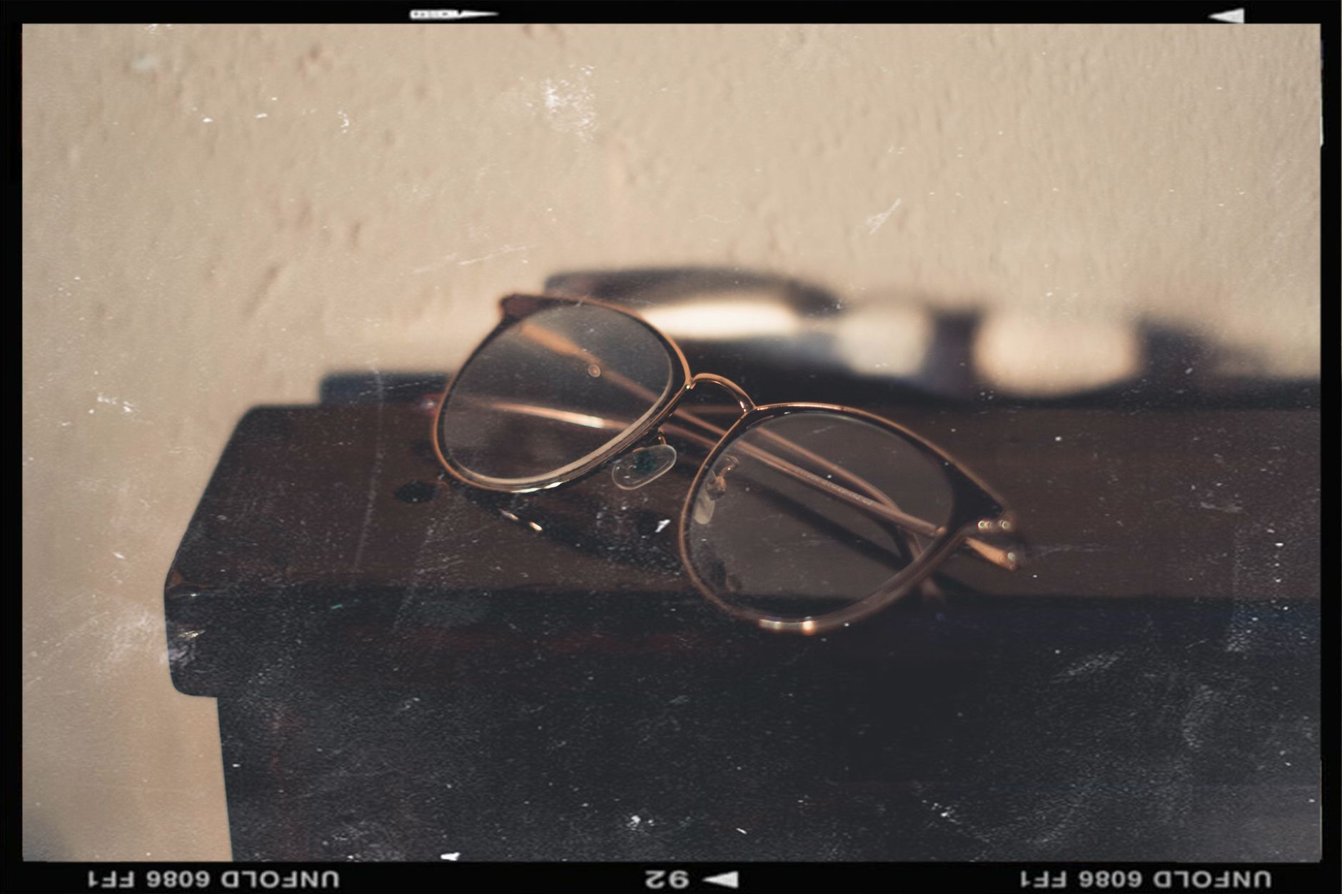 a pair of sleek smart glasses resting on a wooden surface beside a folded prescription lens case, soft natural light from a nearby window