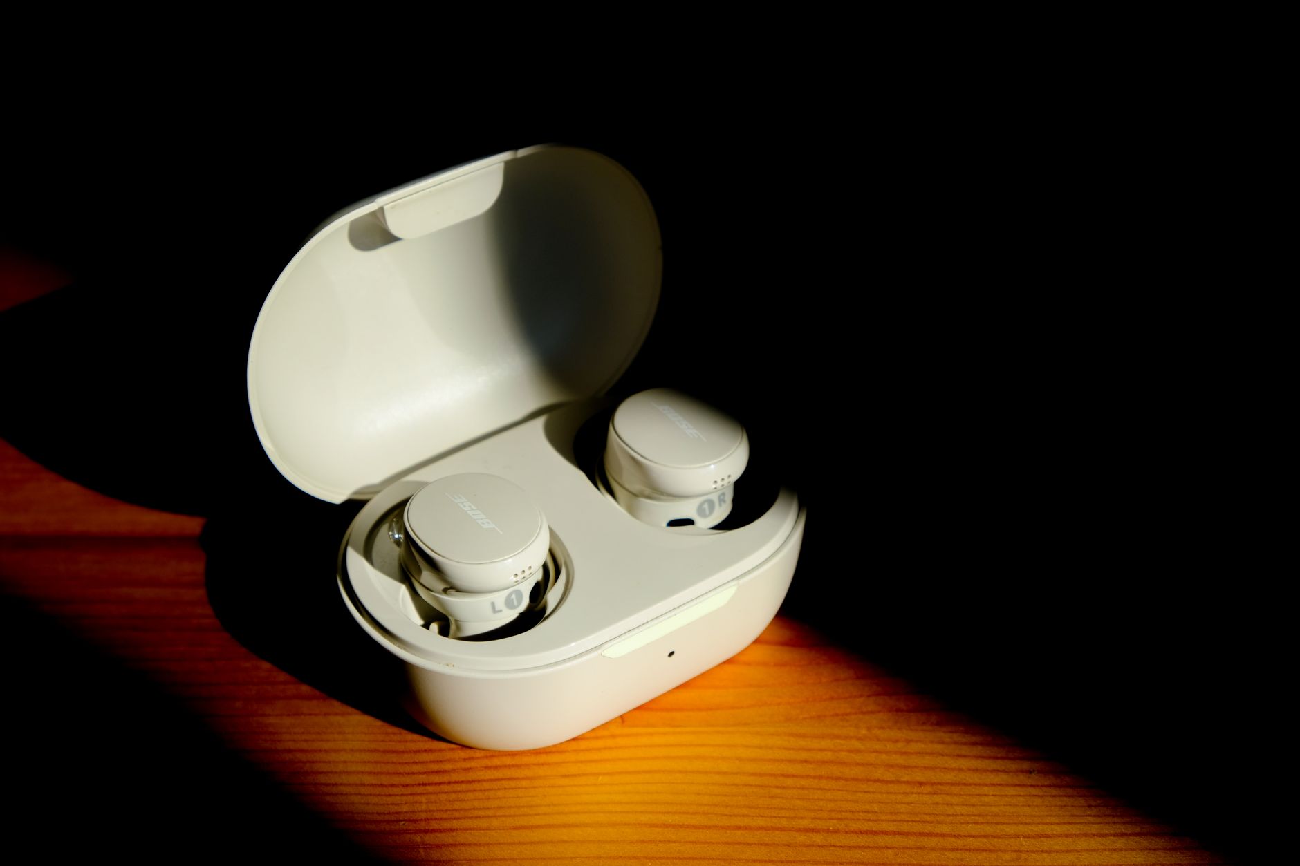 a pair of slim, modern eyeglasses resting on a matte surface next to a small wireless charging case in a sparse industrial design studio