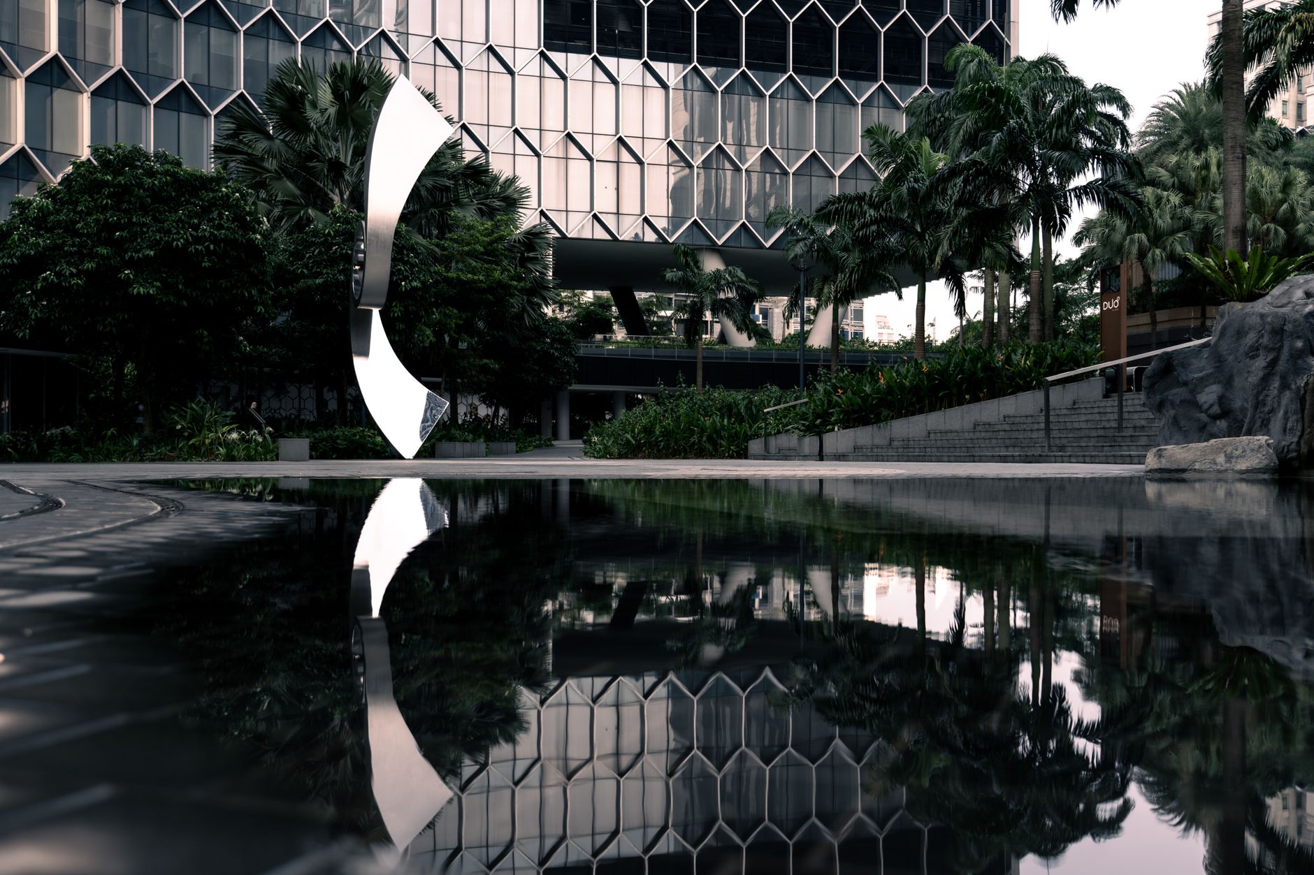 exterior of a large corporate technology campus with glass facade buildings reflected in a courtyard water feature at golden hour
