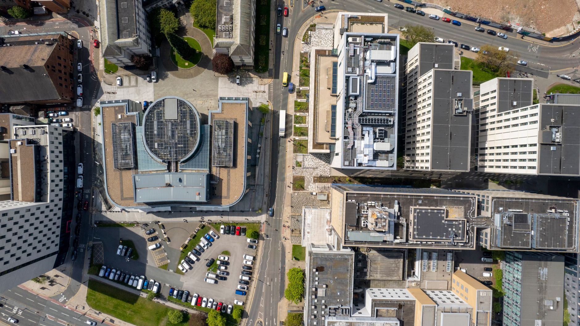 aerial view of a modern European urban technology campus with glass office buildings and rooftop solar panels under overcast skies