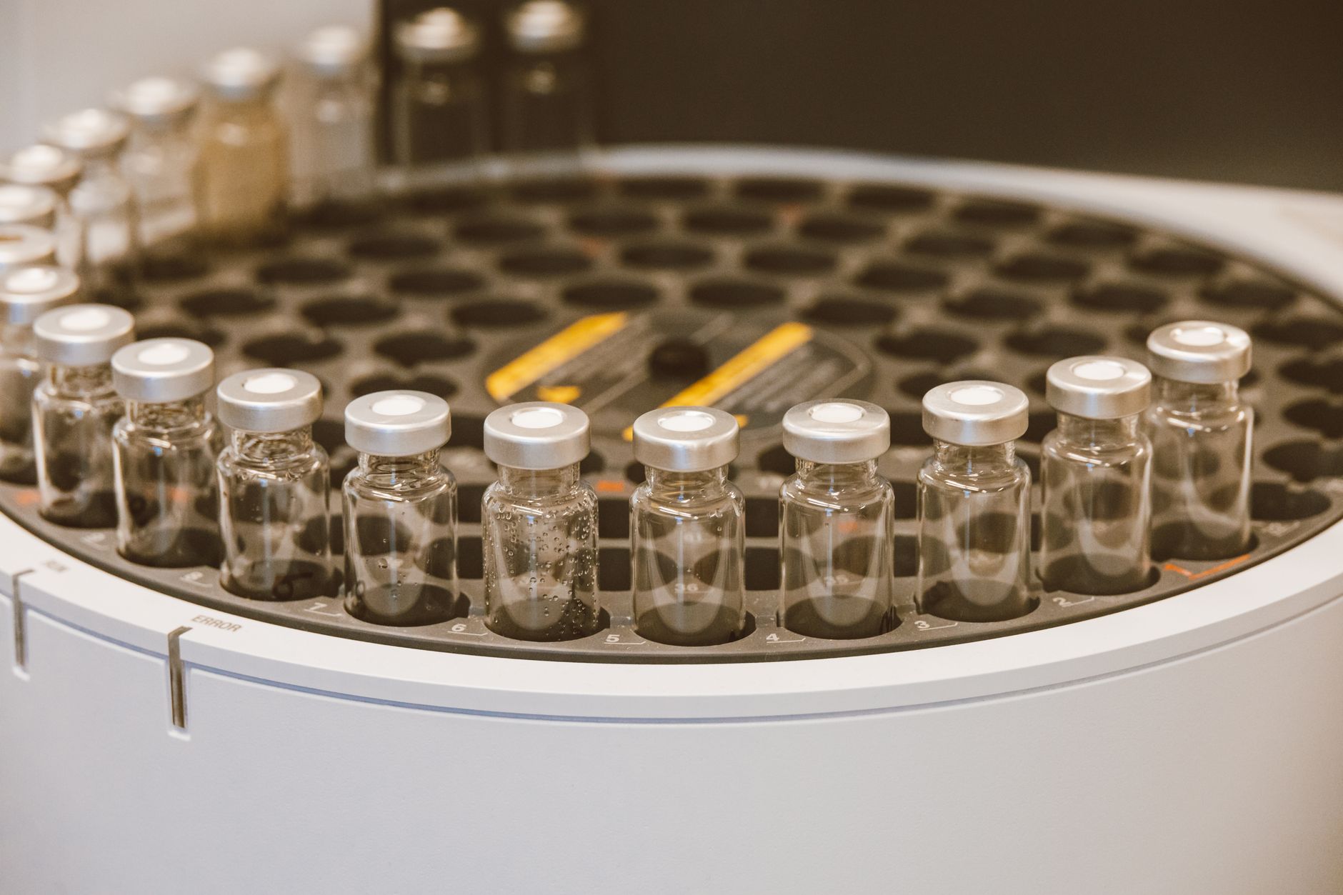 close-up of a laboratory nanoparticle synthesis setup with glass vials, pipettes, and microscopy equipment on a sterile white bench