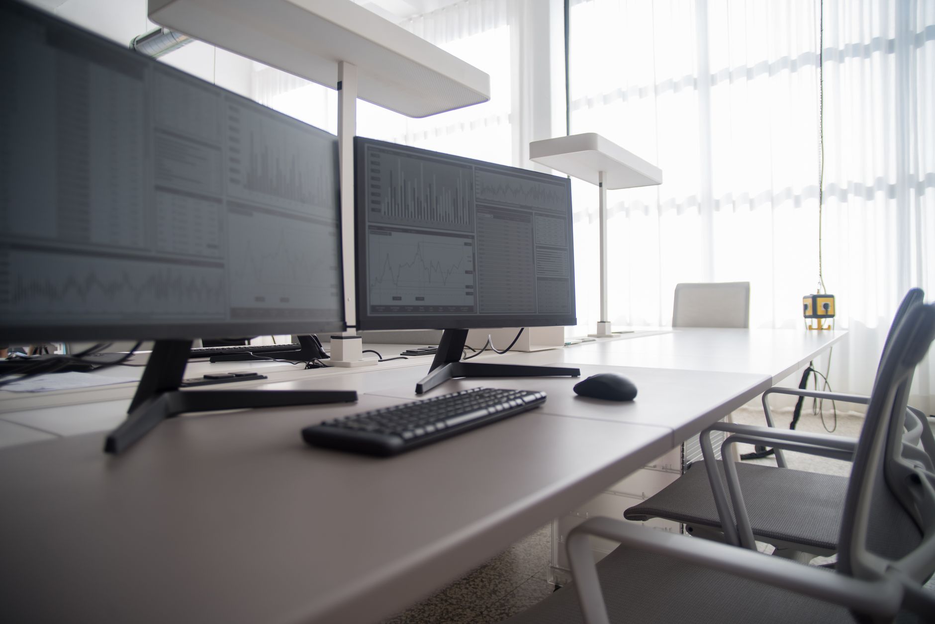 a modern open-plan tech office interior in a Manhattan high-rise, with standing desks, dual monitors, and floor-to-ceiling windows overlooking the city grid below