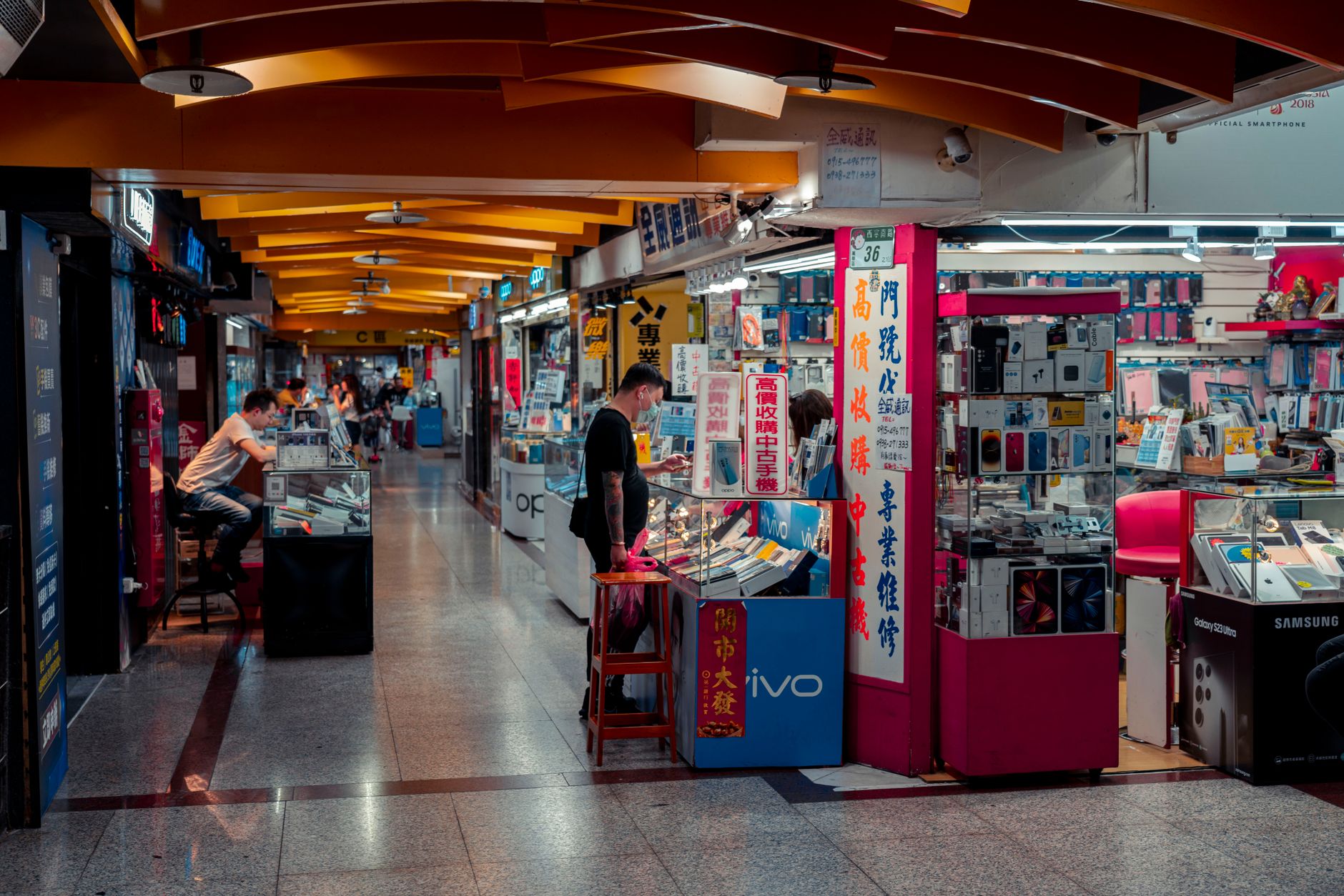 rows of Android smartphones on a retail display shelf in a consumer electronics store, varying models lined up facing forward