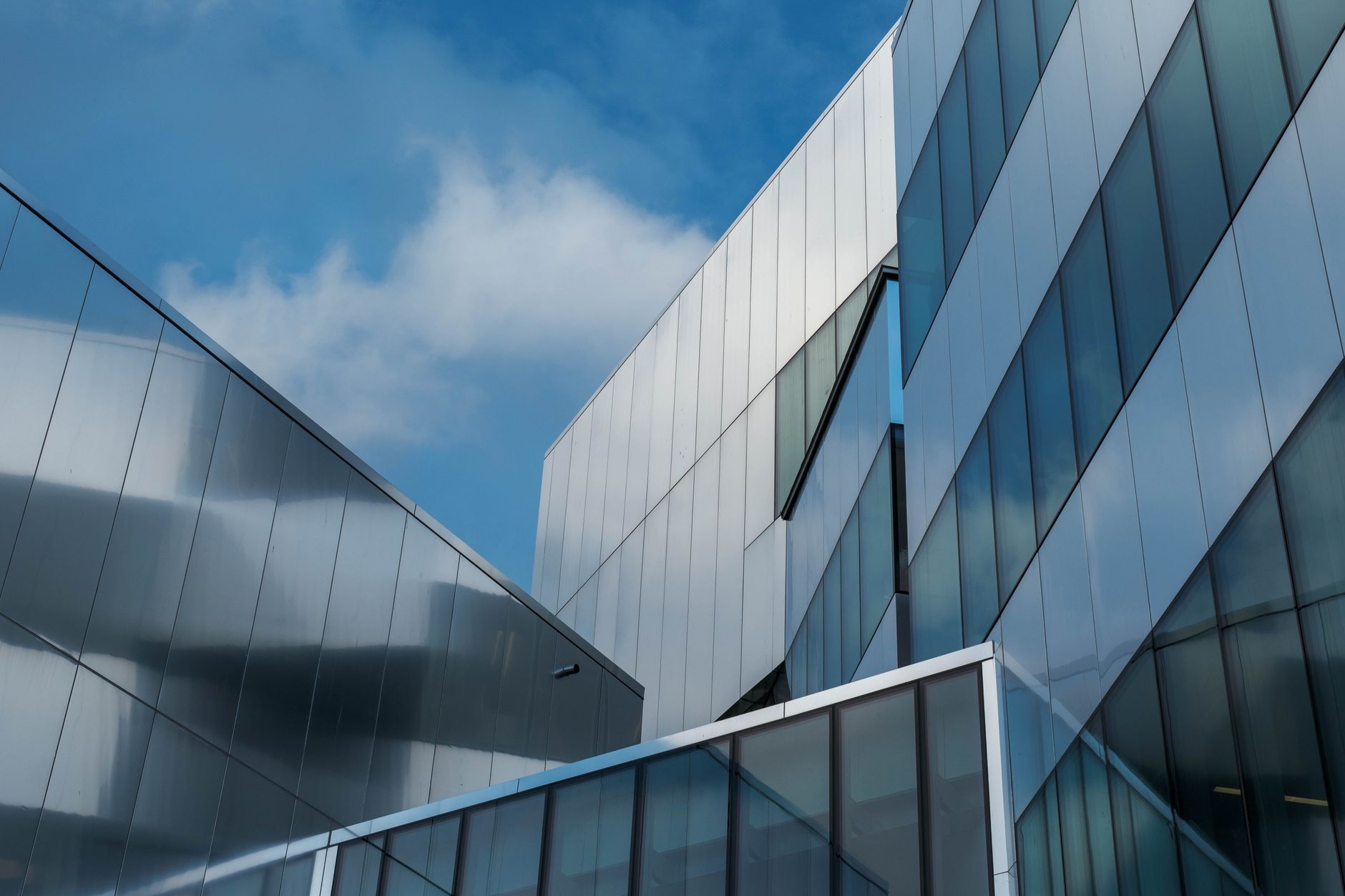 a wide-angle view of a modern glass-and-steel corporate campus at dusk, exterior lit from within, with empty parking lots and a clear sky overhead