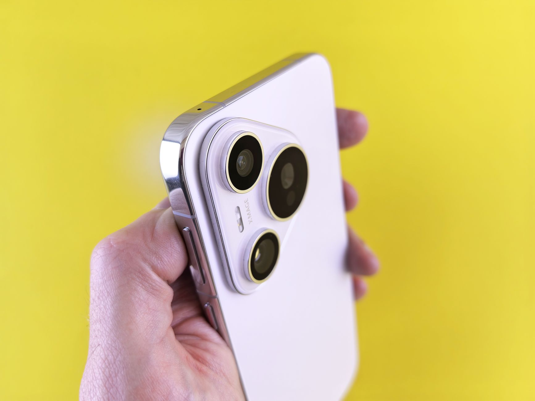 a close-up of a smartphone camera module with multiple lenses, resting on a reflective white surface in a product studio setting