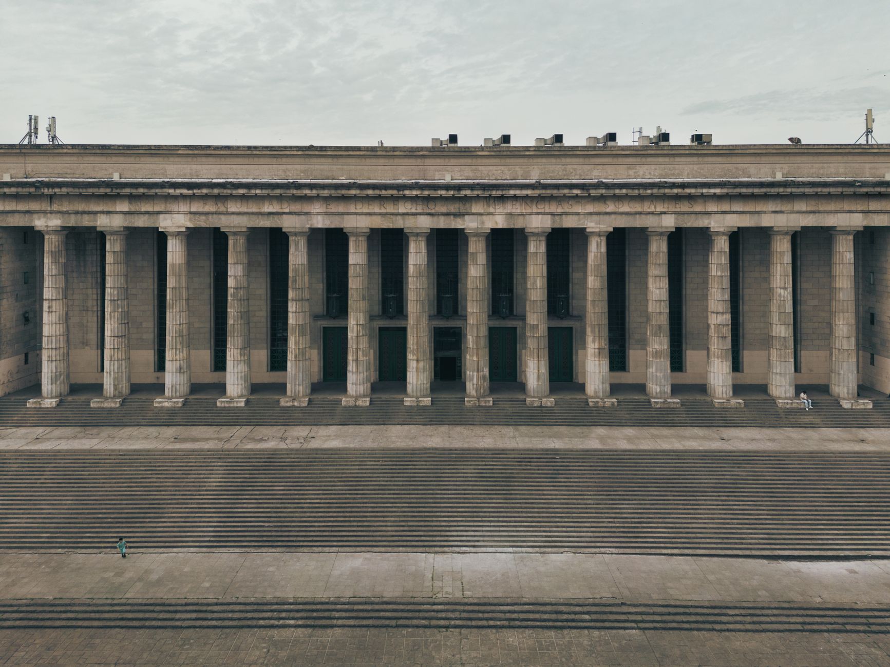 a federal courthouse exterior in early morning light, stone columns and wide steps in the foreground, a busy urban street visible in the background