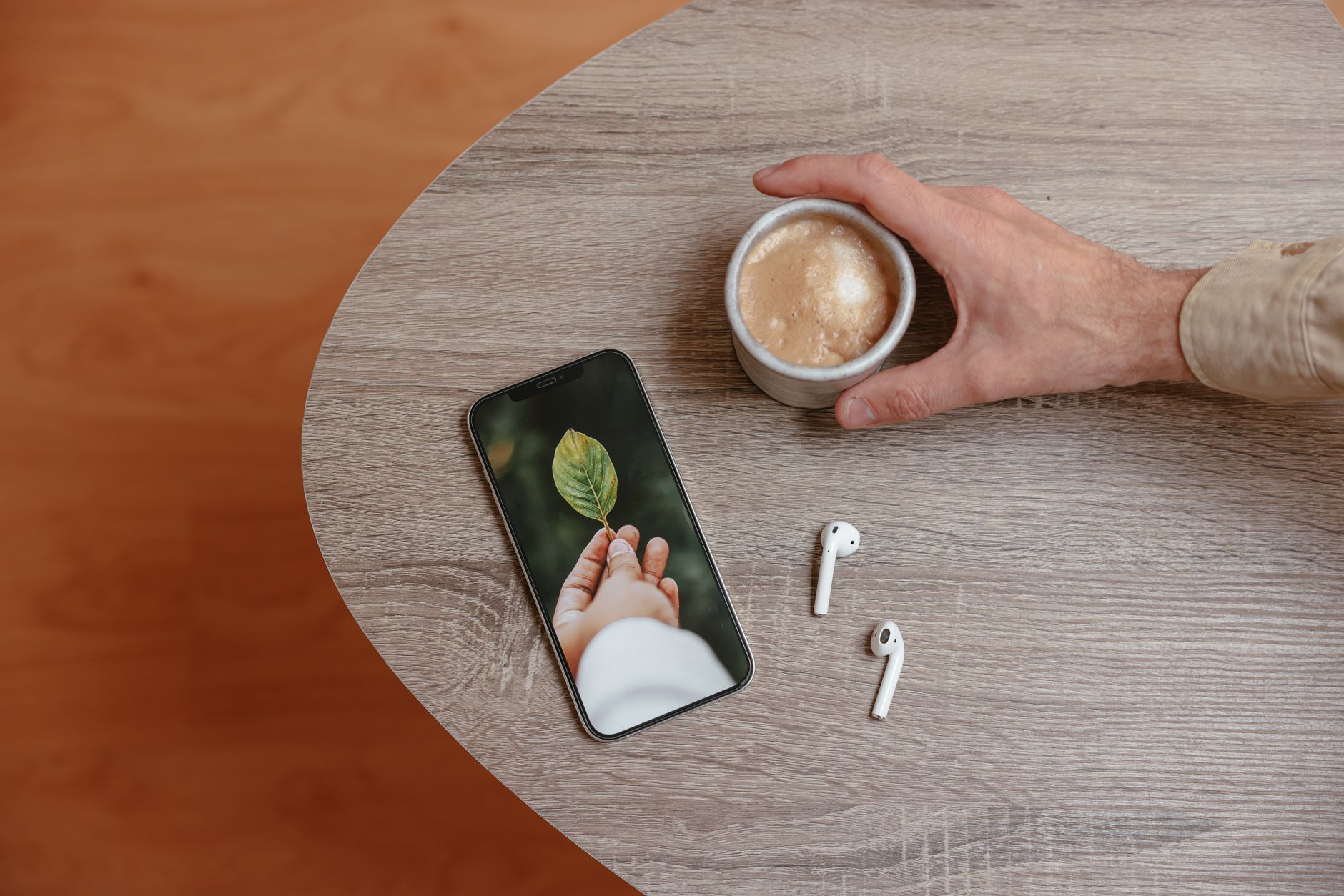 a close-up of a smartphone screen showing a blockchain transaction confirmation for a stablecoin transfer, resting on a wooden desk beside a coffee cup