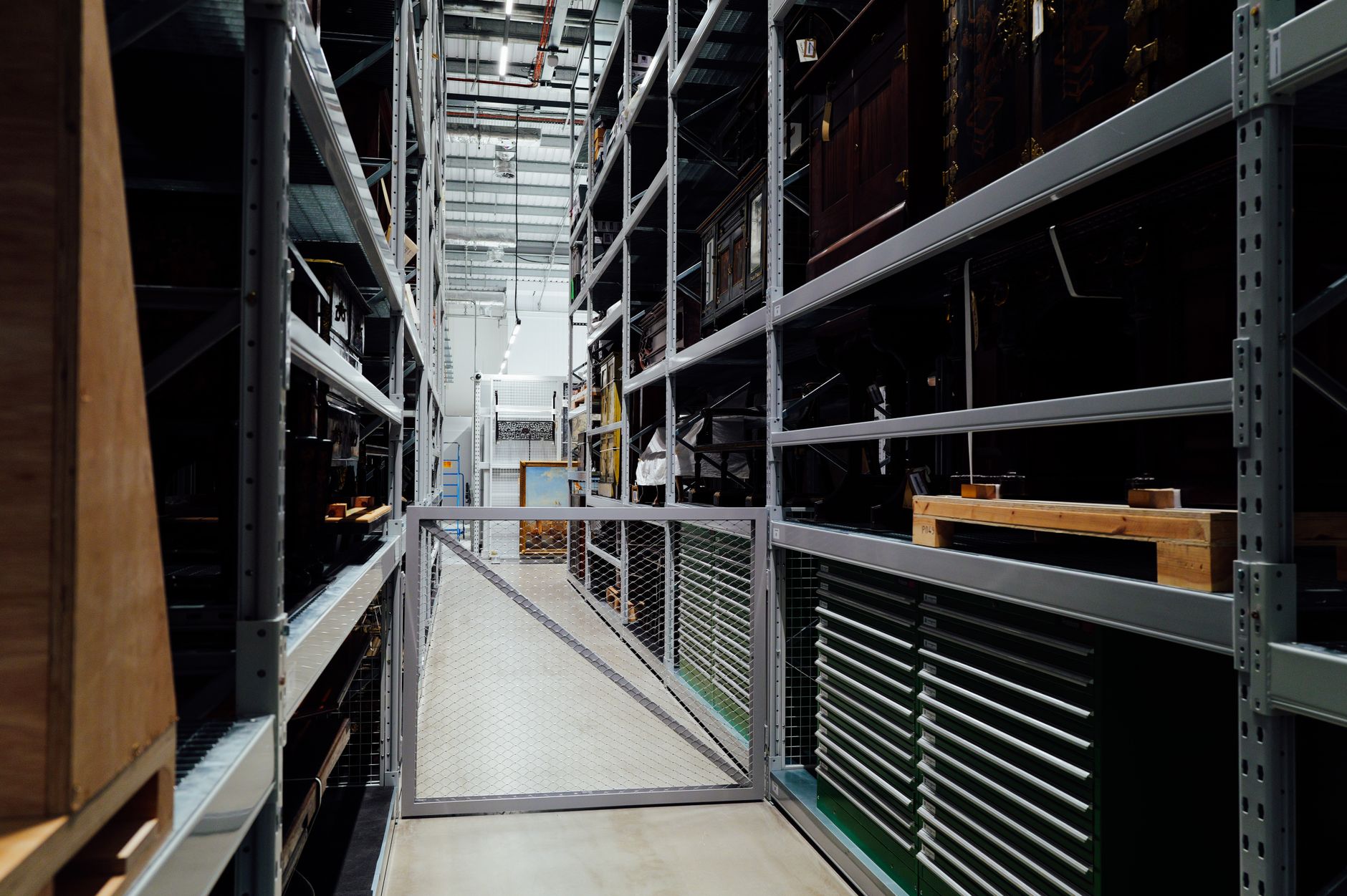 rows of stainless steel primate housing units inside a temperature-controlled biomedical research facility, empty corridors visible in background