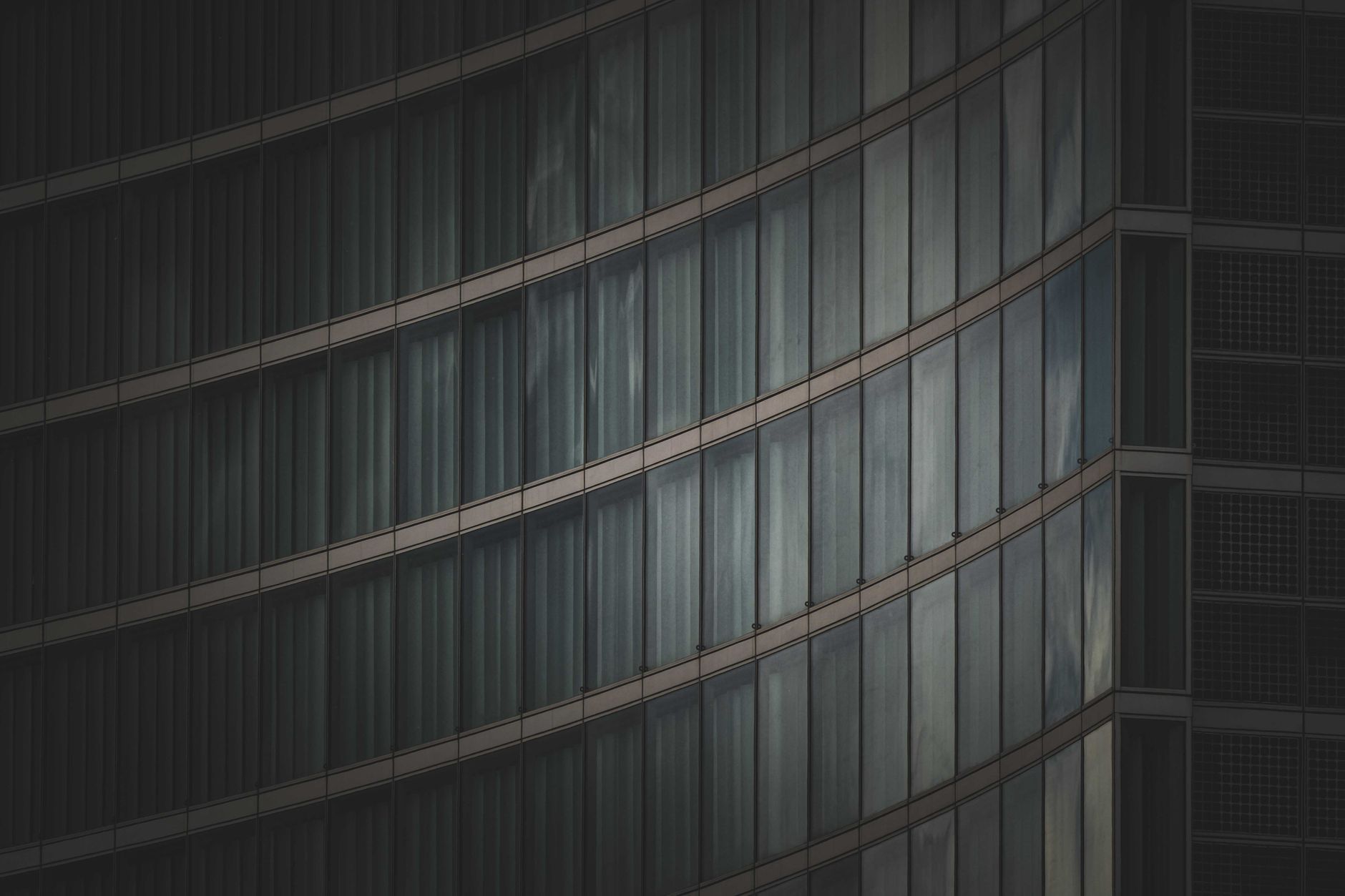 exterior of a large modern cancer research hospital building at dusk, glass facade reflecting city lights